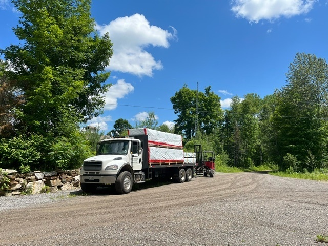 A crated bunkie kit being lifted off a flatbed trailer with a forklift