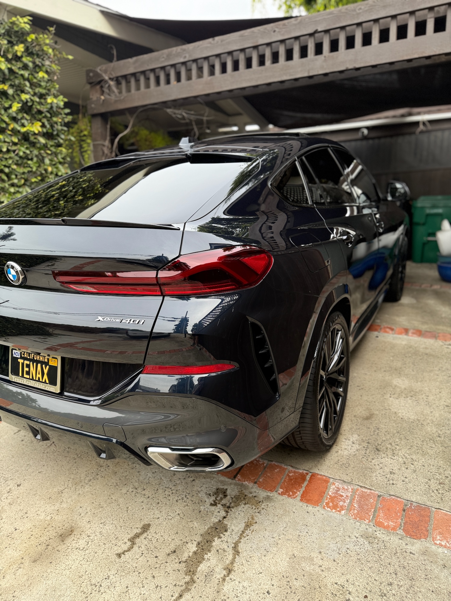 High-gloss black BMW X6 M50i shining in a driveway after professional mobile detailing service.