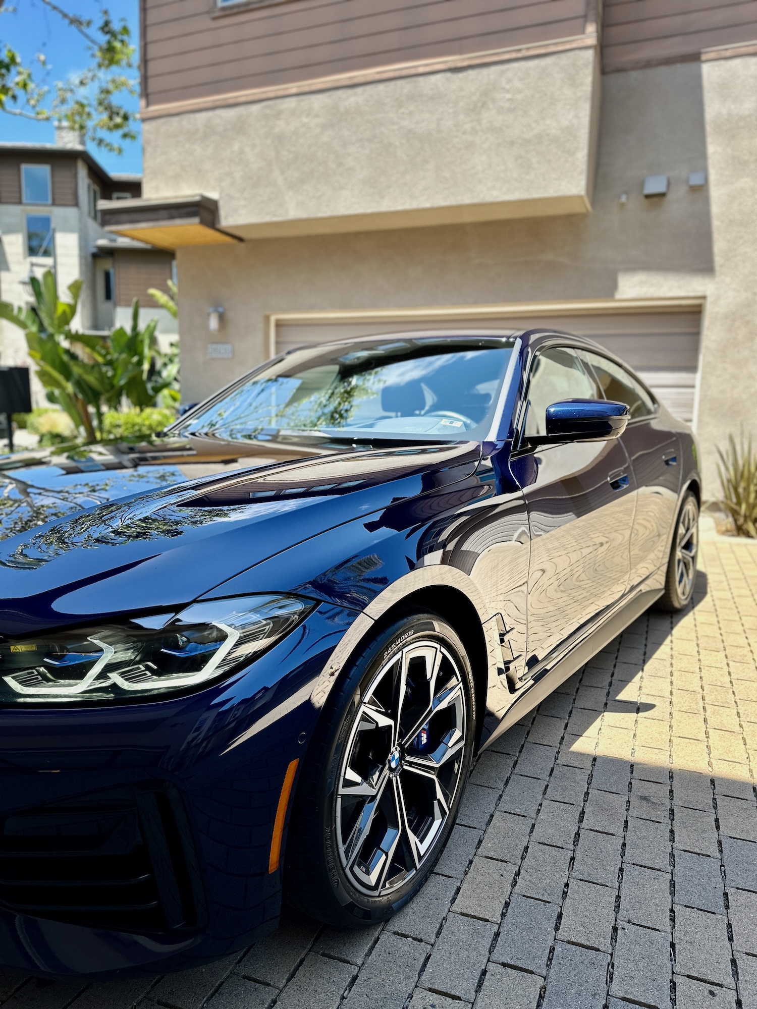 Sleek BMW i4 M50 with a brilliant blue finish, perfectly polished and reflecting sunlight after expert detailing.