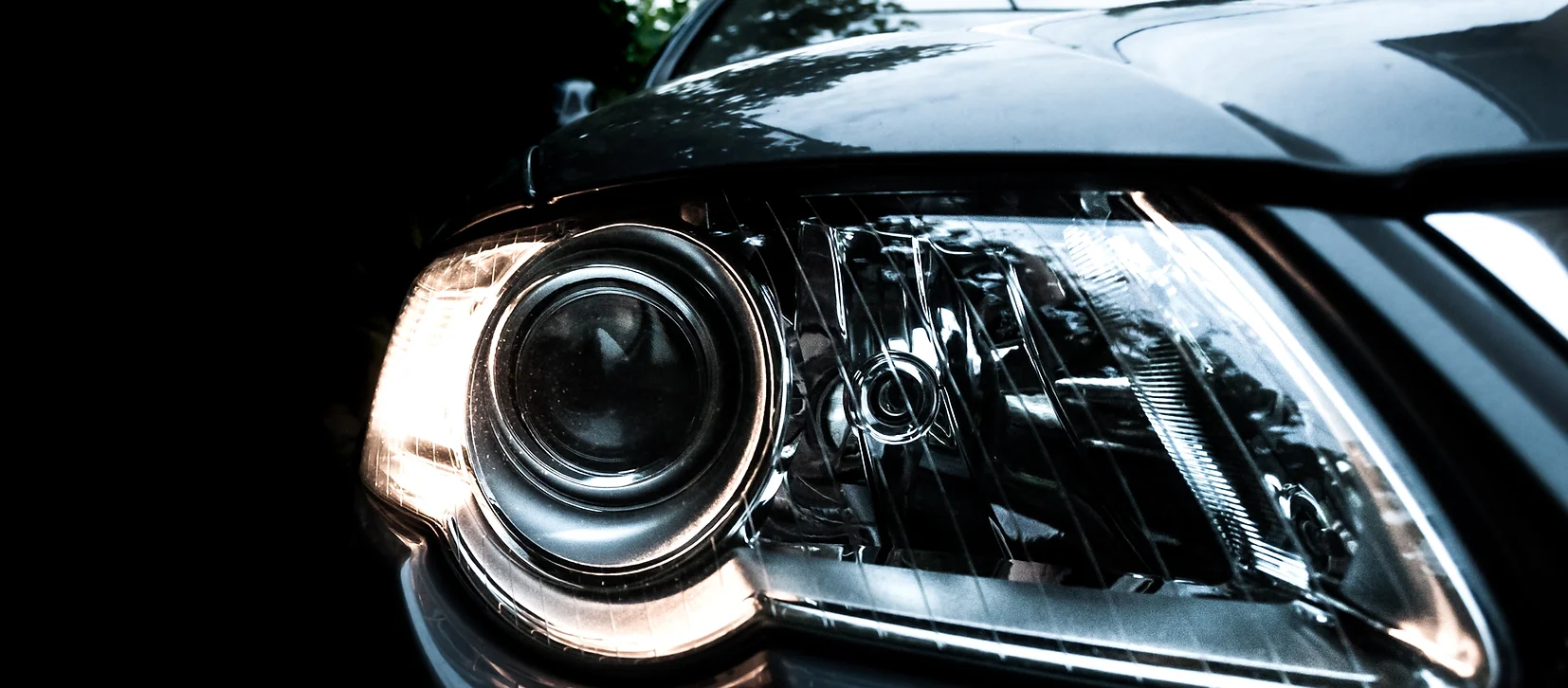 Close-up of a polished and restored headlight lens on a black vehicle, highlighting clarity and detail after headlight restoration service.