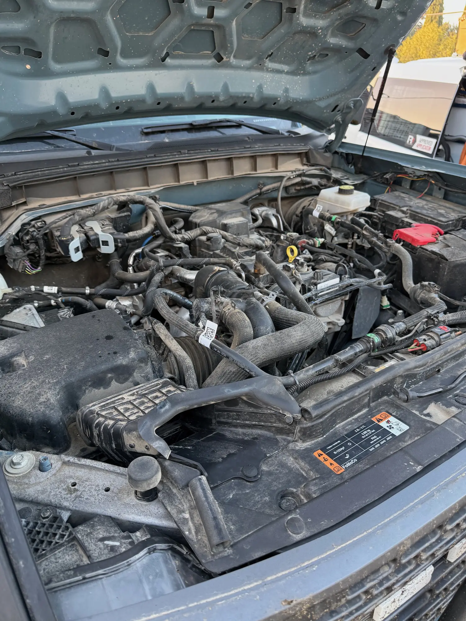 Dusty and grease-covered engine bay before steam cleaning and detailing service.