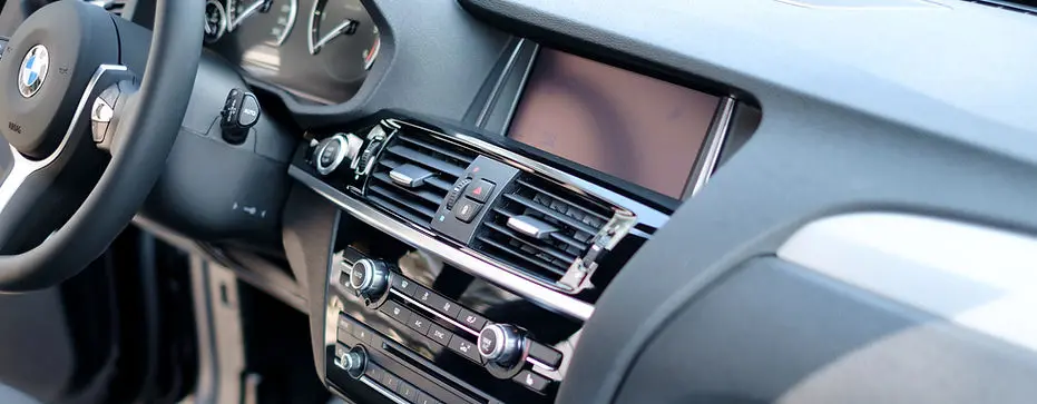 Polished BMW dashboard and center console after interior detailing, showing clear screens and clean surfaces.