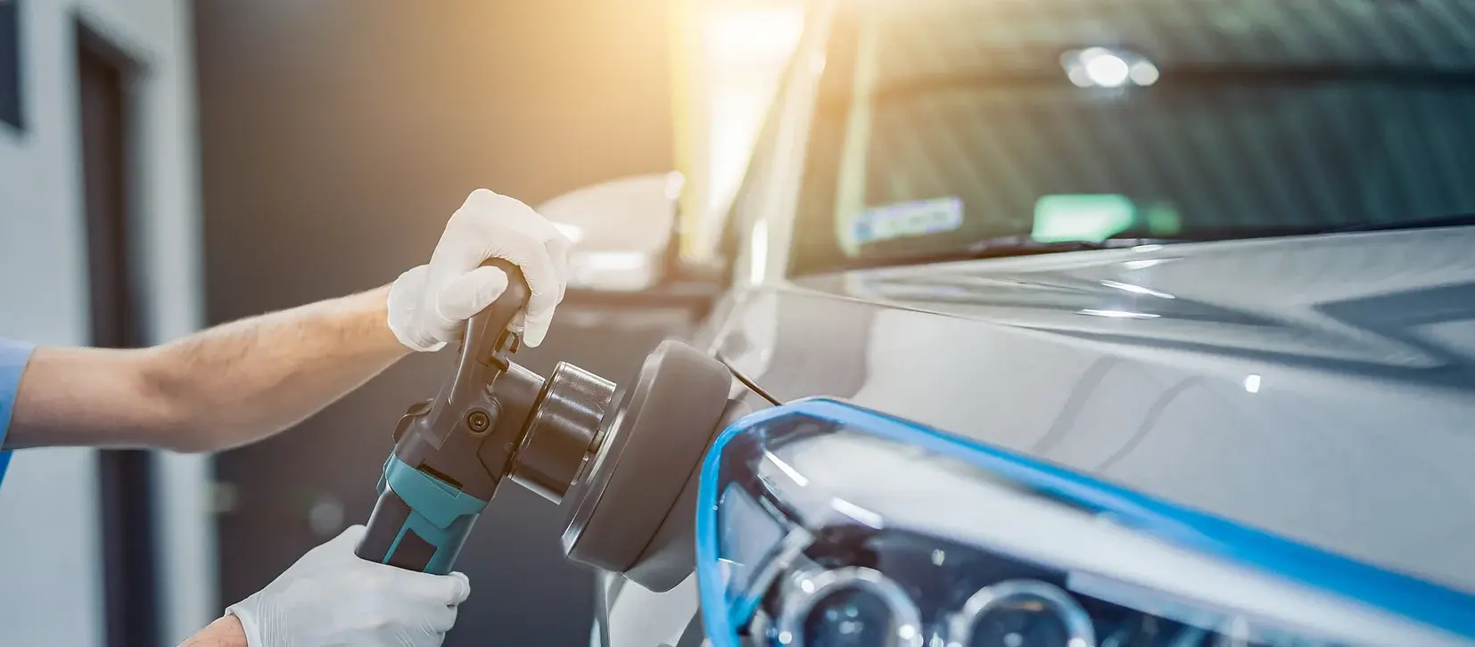 Detailing professional using a dual-action polisher on a silver vehicle for a high-gloss finish during paint correction."