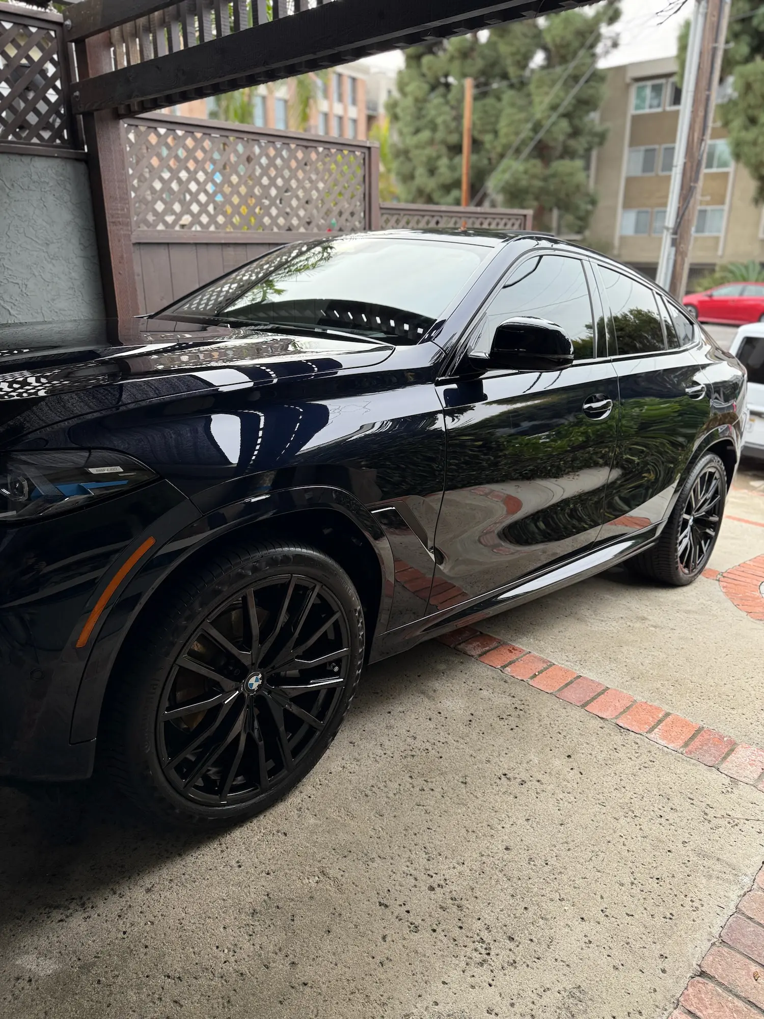 Glossy black BMW X6 parked in a driveway after professional mobile detailing service.