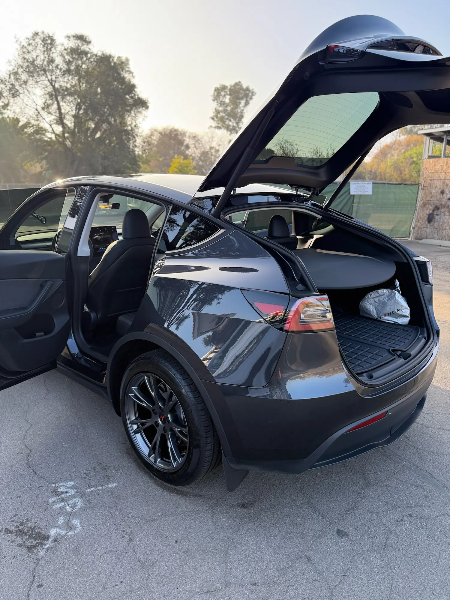 Freshly detailed Tesla Model Y with open doors and trunk, showcasing a clean, glossy exterior and spotless interior.