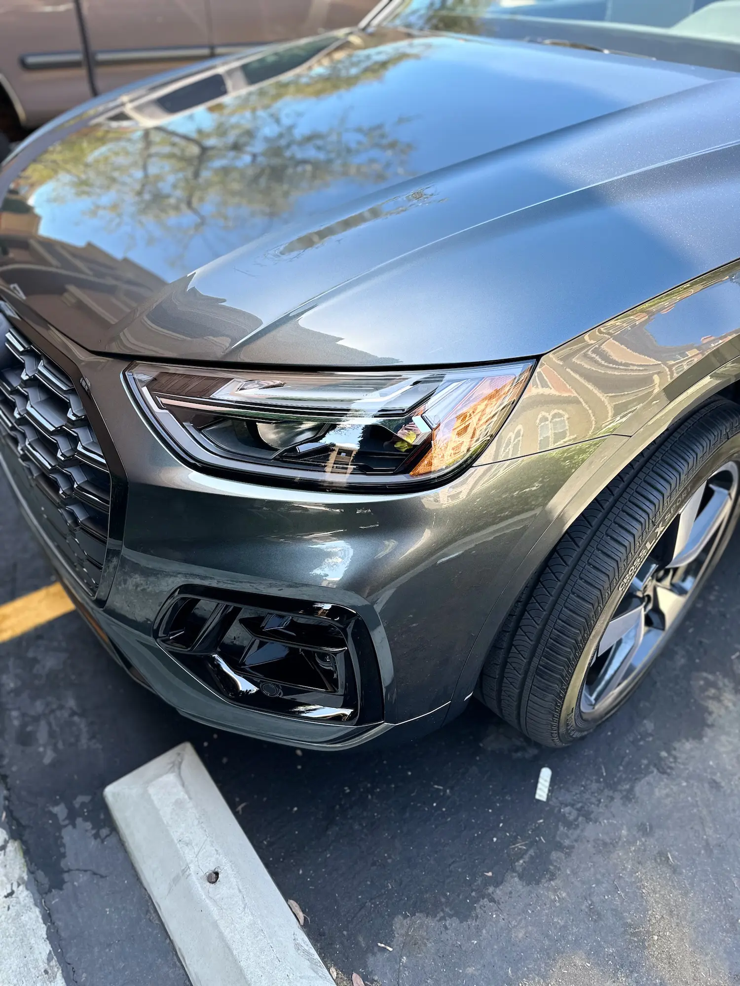 Glossy hood and sharp headlights of a metallic gray Audi SUV.