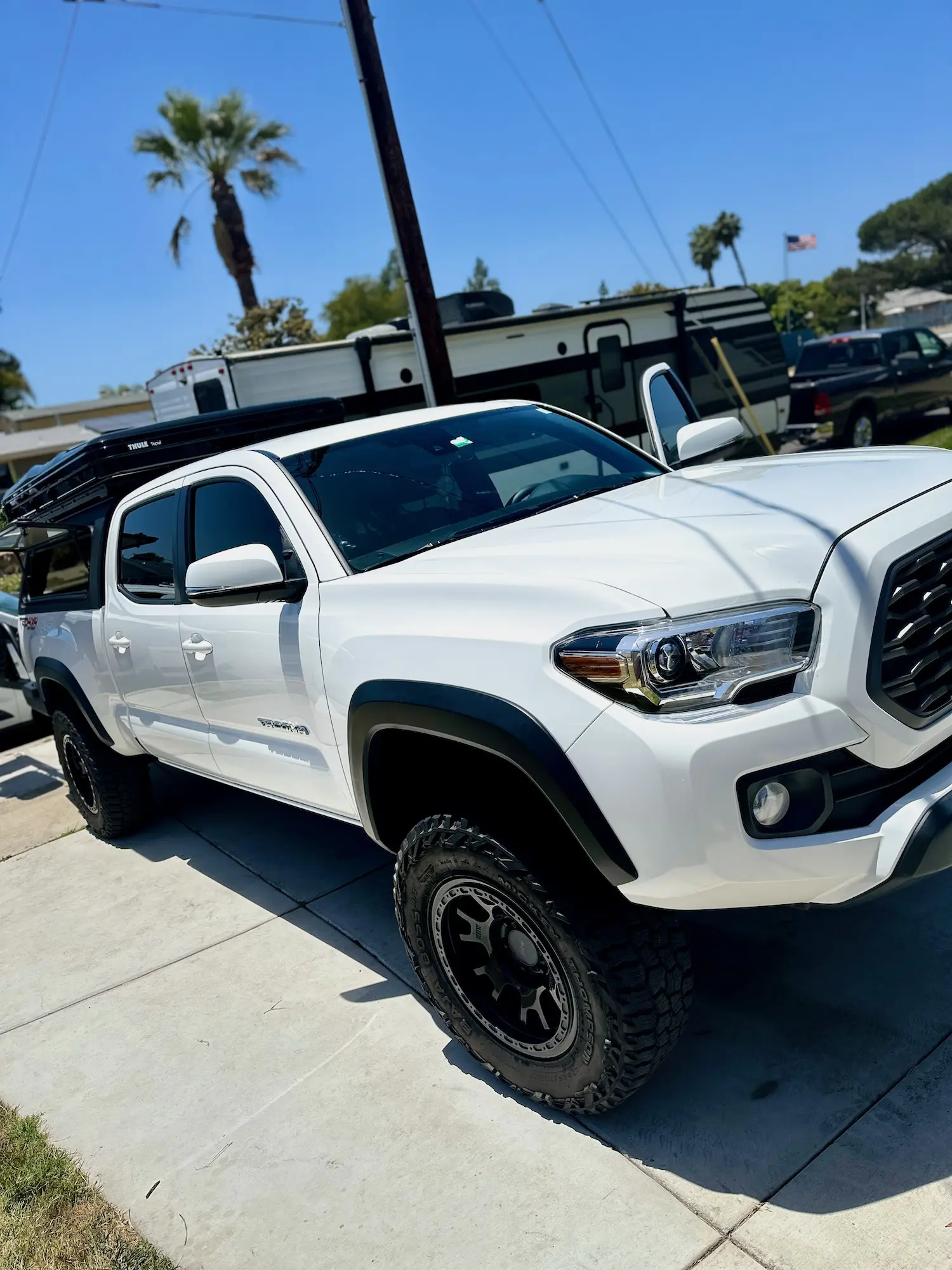 Lifted Toyota Tacoma TRD Pro parked in a sunny driveway, showcasing fresh detail, black off-road wheels, and rooftop rack.