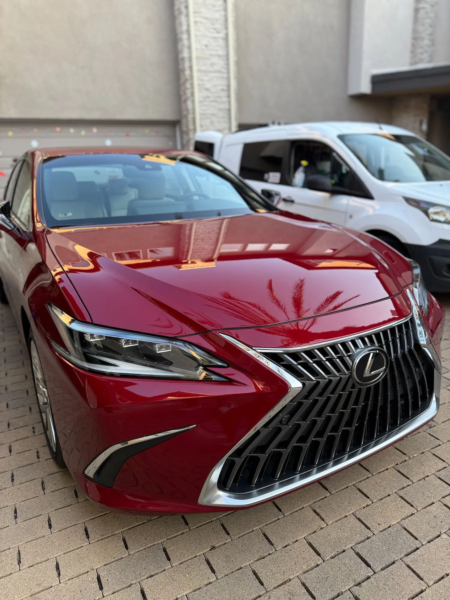 Front view of a freshly detailed red Lexus sedan with a shiny grille.