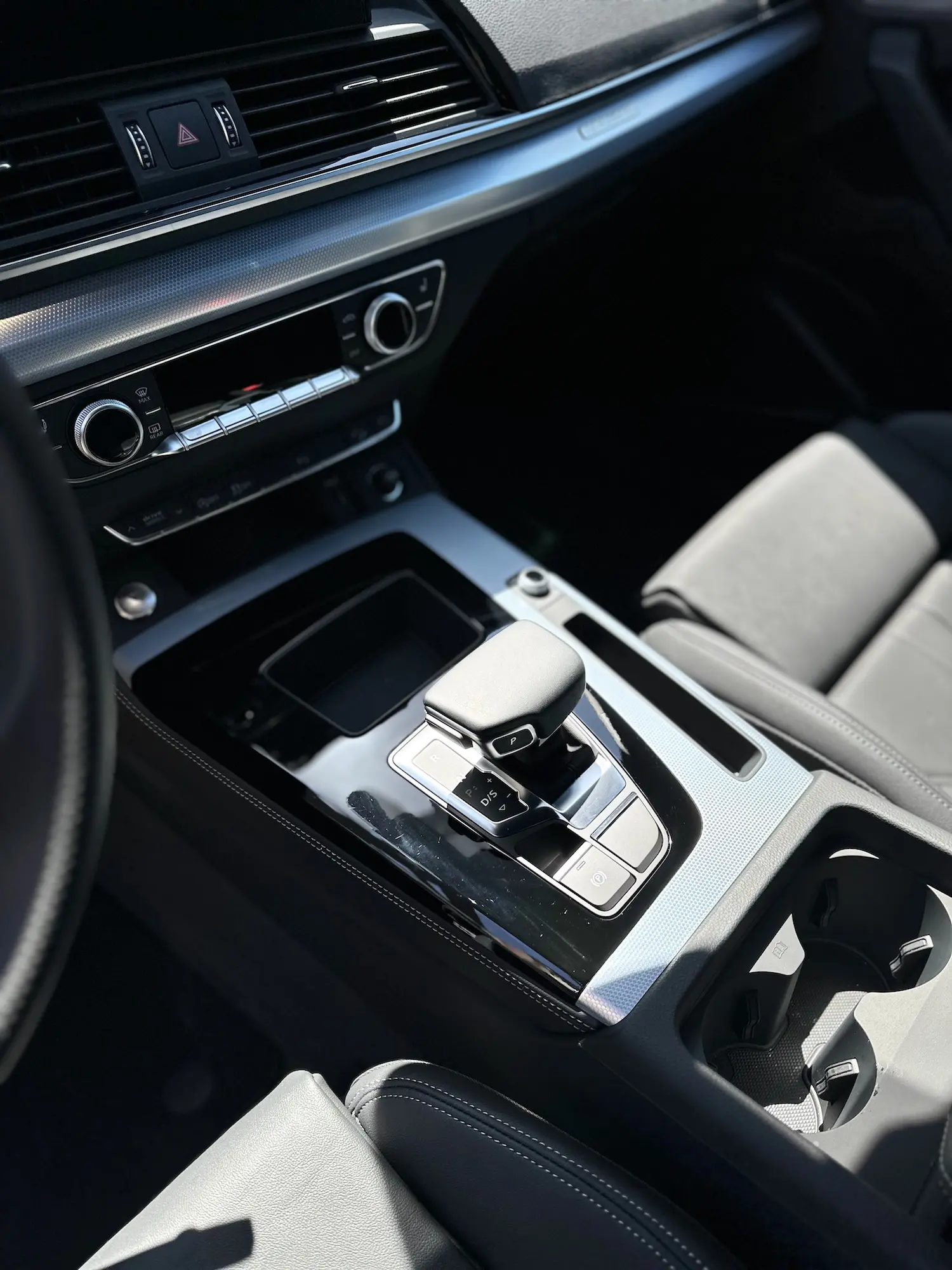 Close-up of a luxury vehicle interior featuring a clean dashboard, cup holders, and a polished gear shifter after detailing.