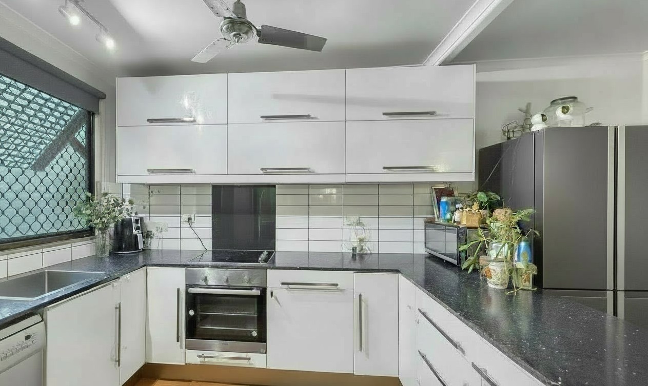 Renovated kitchen at 76/16 Hudson Fysh Avenue Parap featuring stone benchtops, breakfast bar, stainless steel appliances and open-plan living area