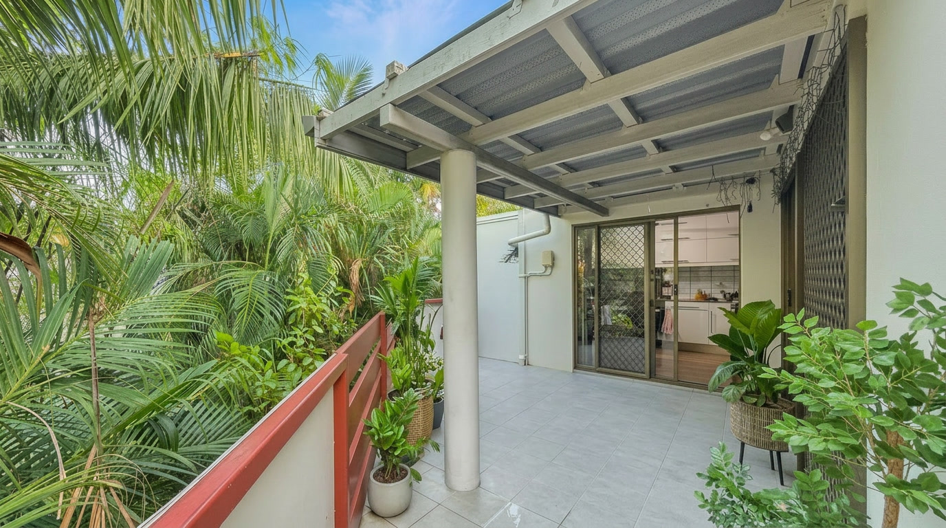 Private covered balcony at 76/16 Hudson Fysh Avenue Parap overlooking lush tropical gardens and connected to the open-plan living area.