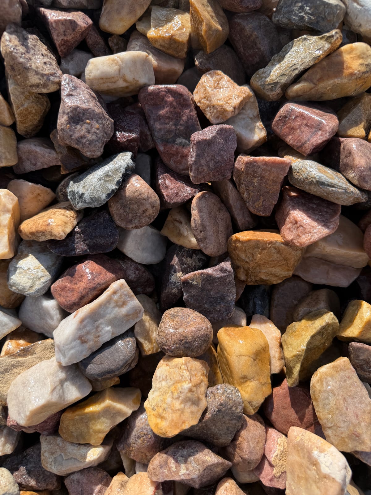 1.5 inch Neapolitan crushed rock in a mix of dark gray, brown, and red tones