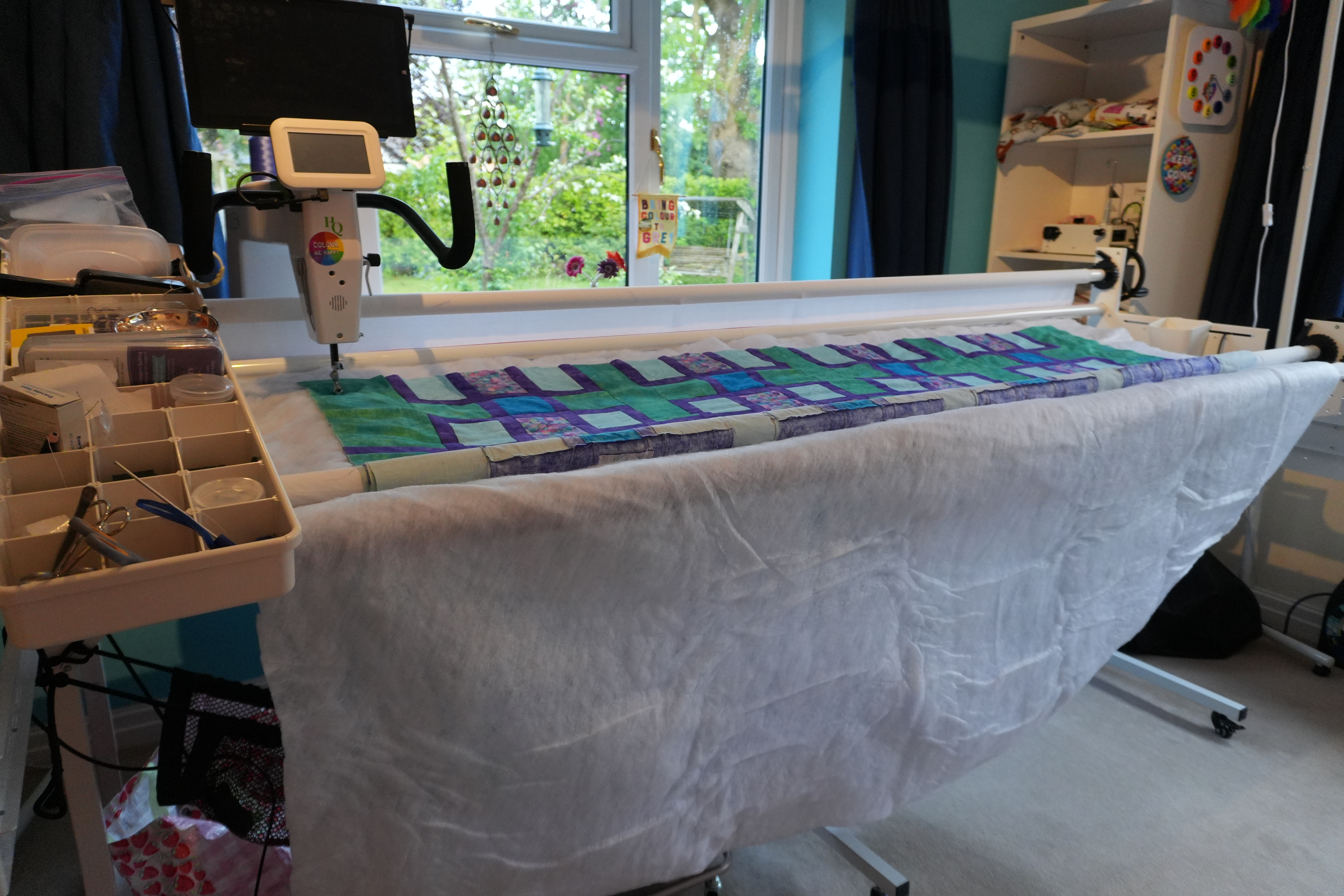 Longarm quilting frame in a sewing studio with a blues and greens quilt loaded