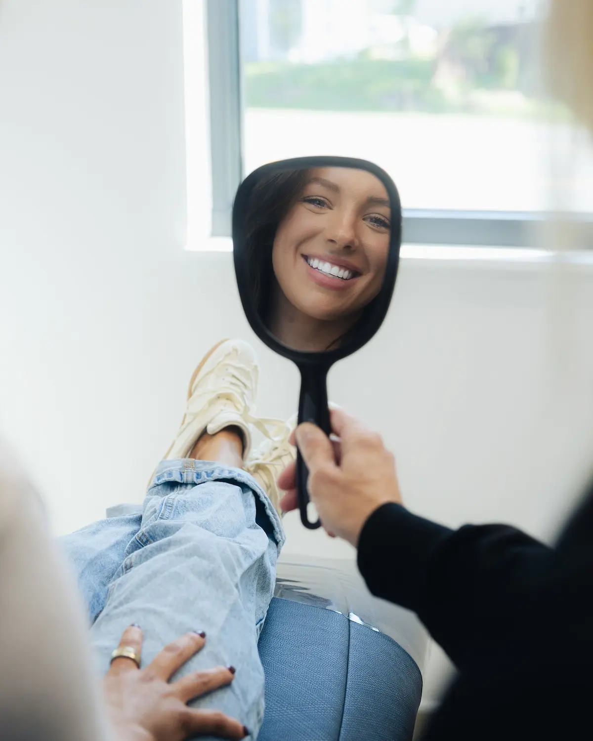 Patient smiling at her reflection in a hand mirror