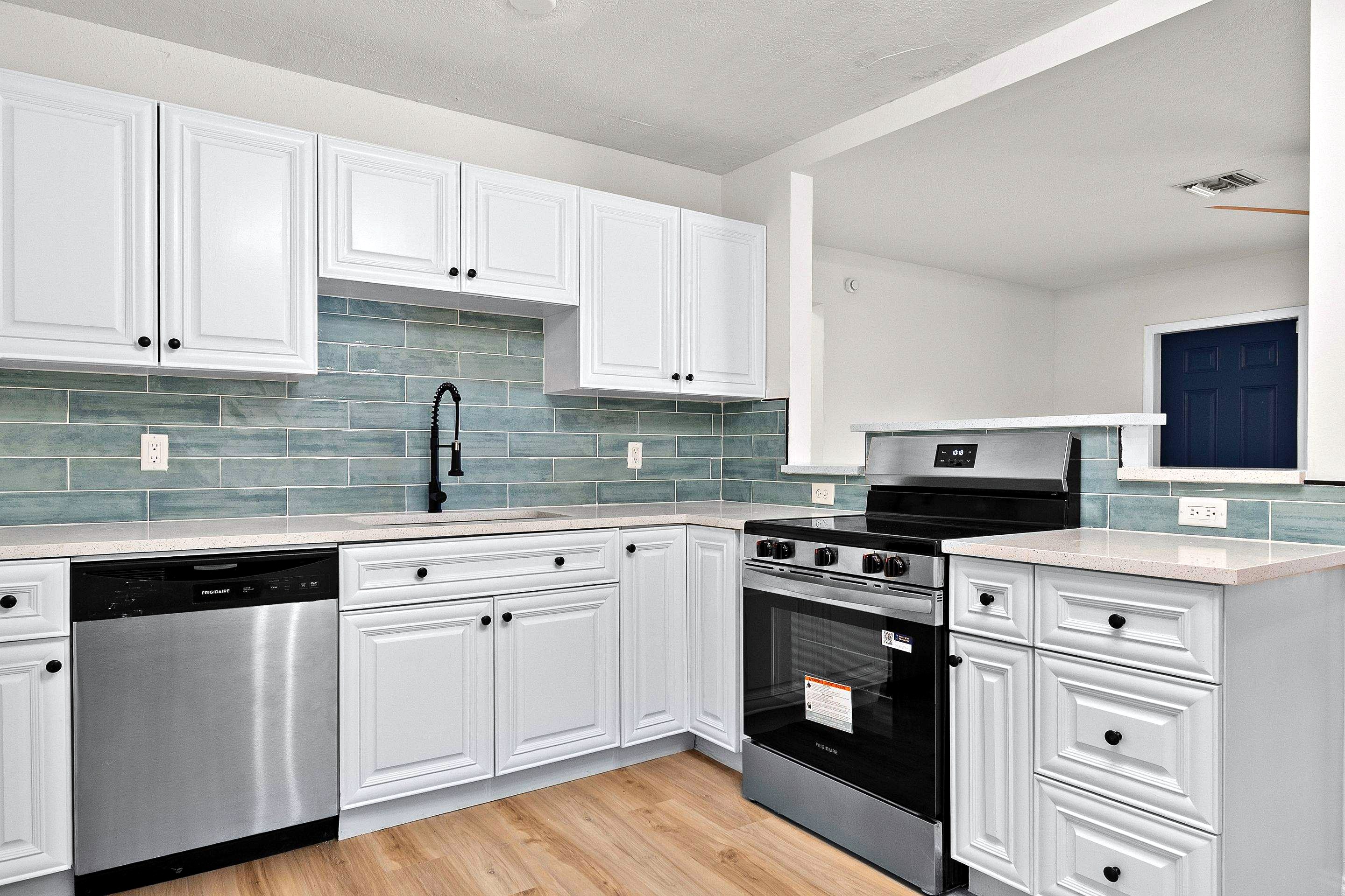 After: remodeled kitchen with quartz top, glass backsplash, black handles and stainless steel appliances