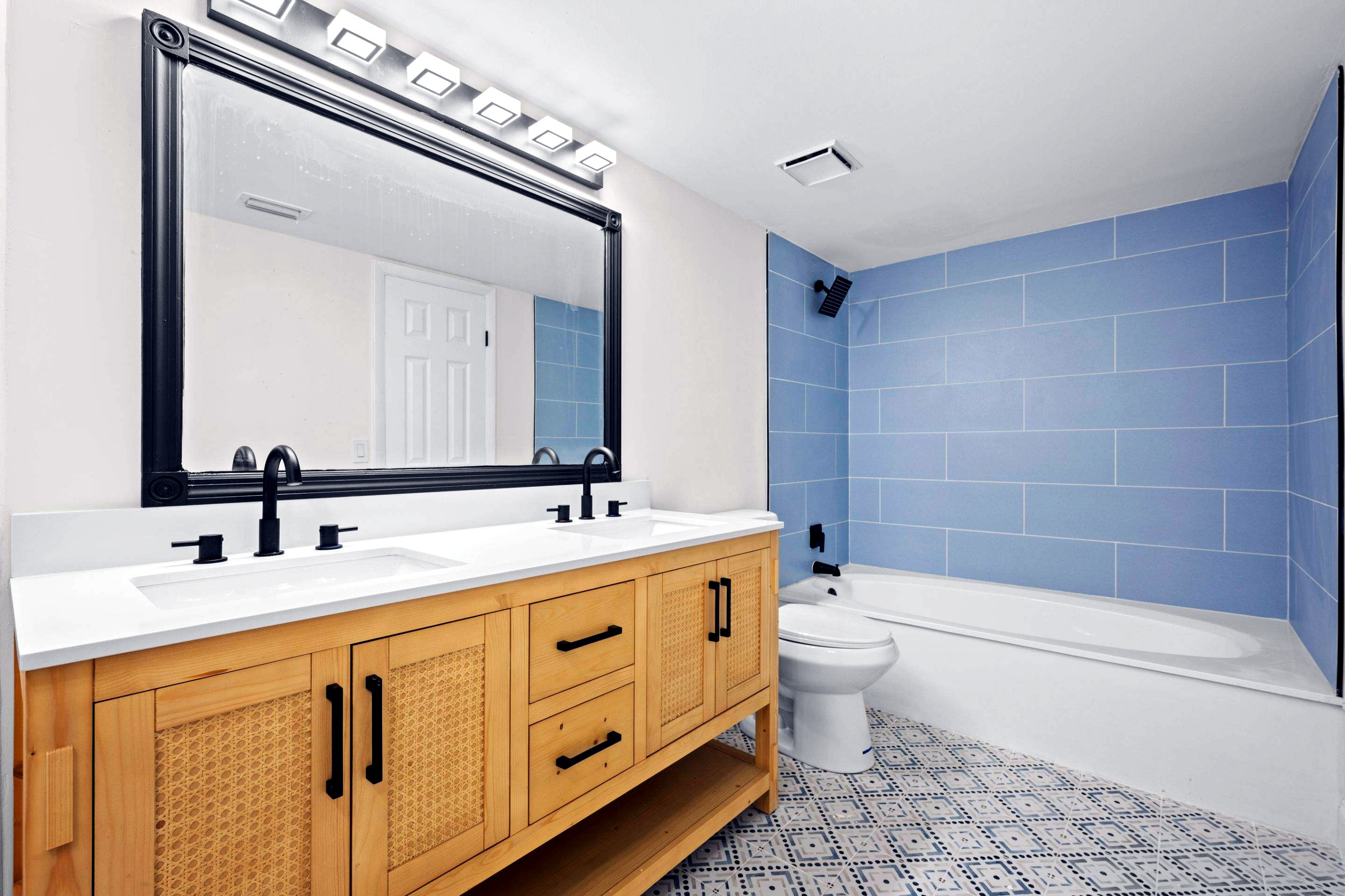 After: remodeled master bath with double vanity, tiled tub surround and patterned floor tile