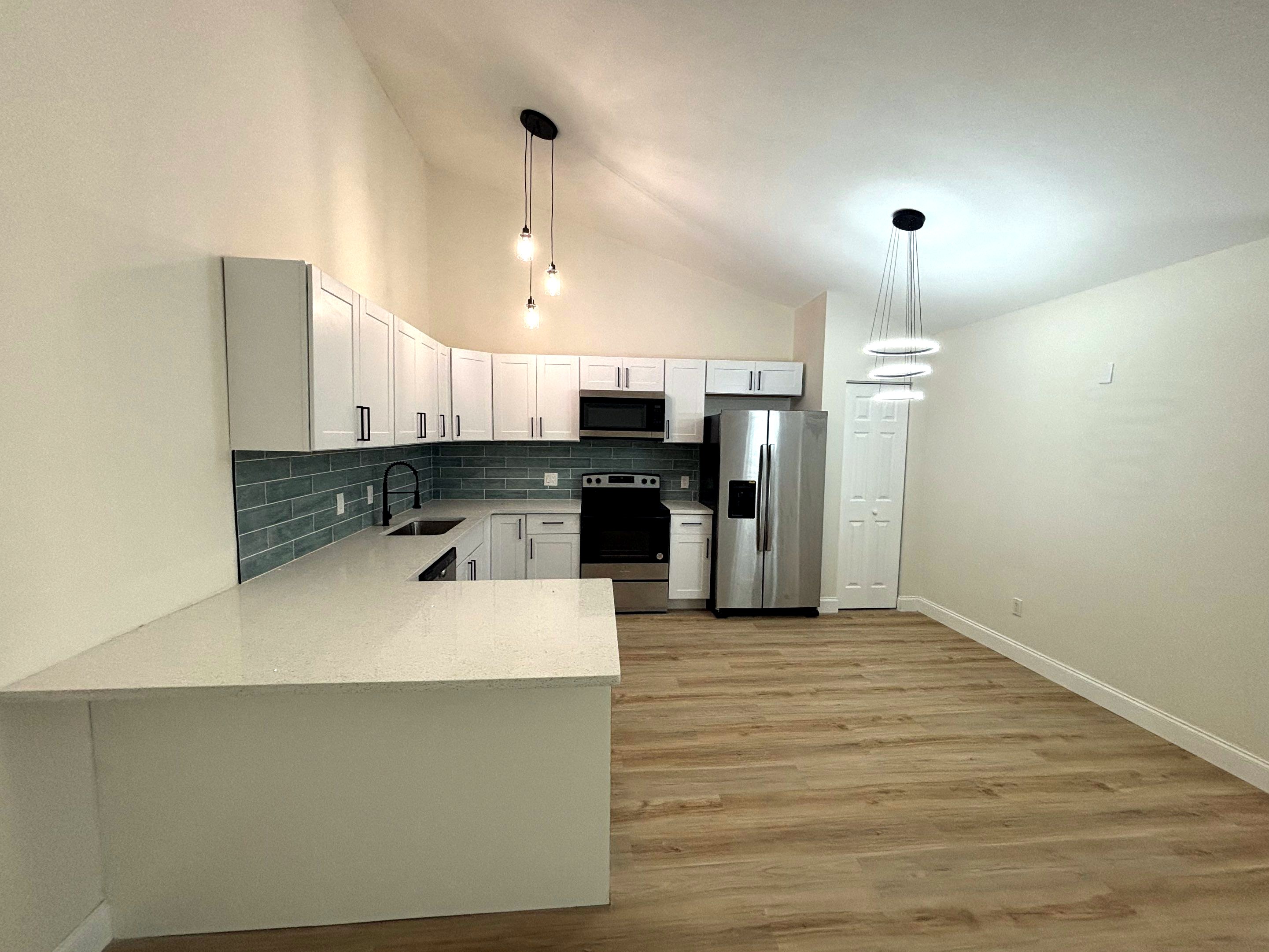 After: white shaker kitchen with soft close, glass backsplash, stainless steel appliances and quartz top with bar