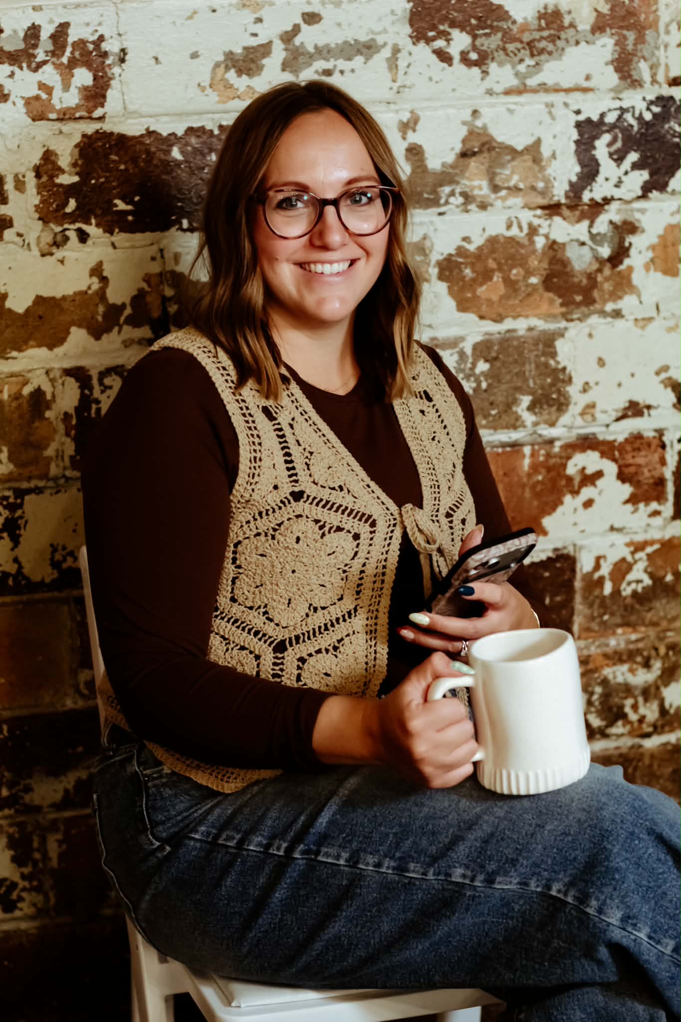 Crista with a coffee mug and phone