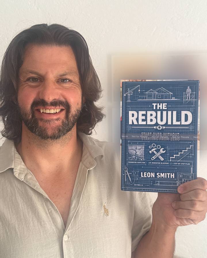 Leon Smith smiling and holding a copy of his book, The Rebuild