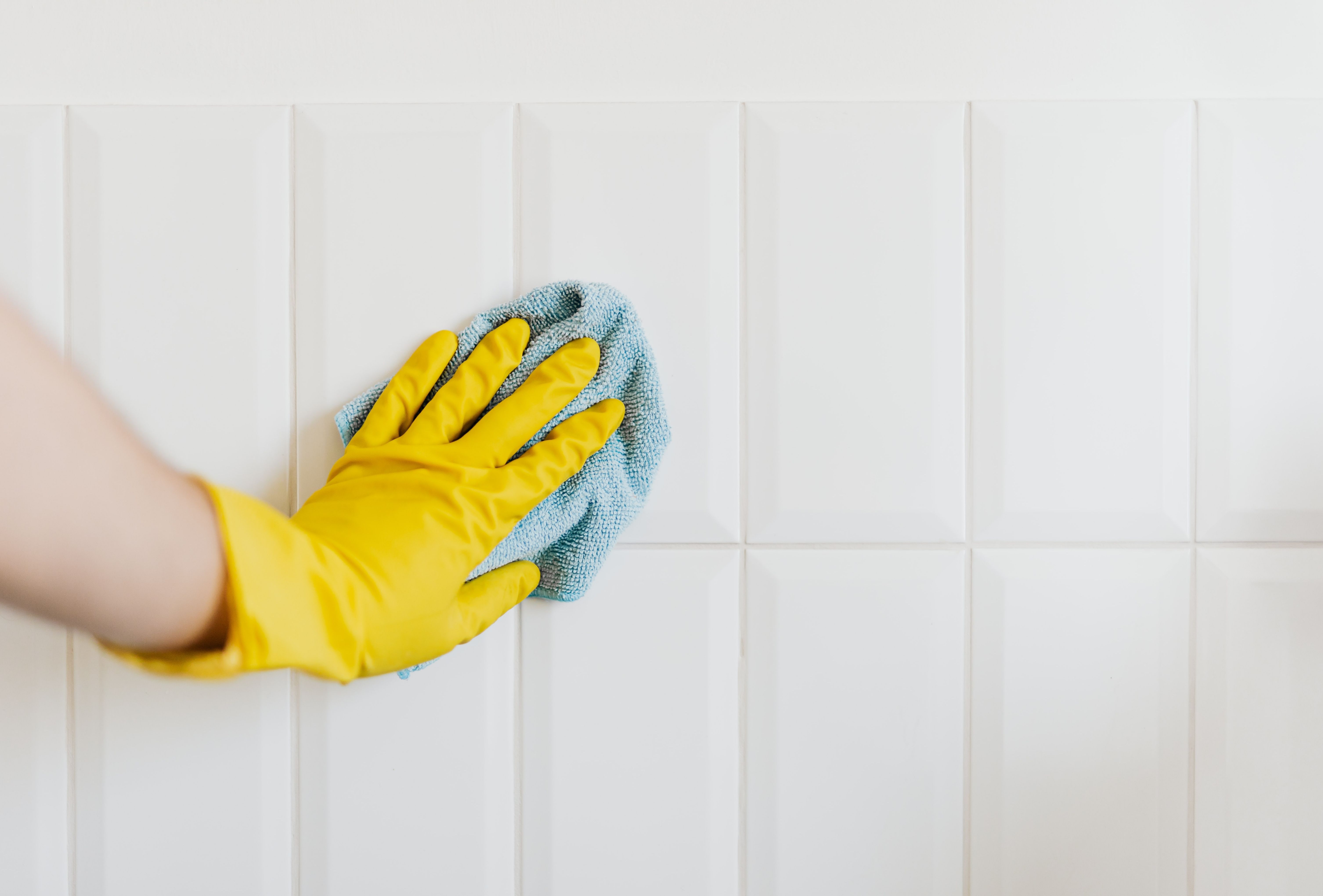 Wiping white tiles with a microfiber cloth, typical of a professional cleaning service near me. Wiping white tiles with a microfiber cloth, typical of a professional cleaning service near me.