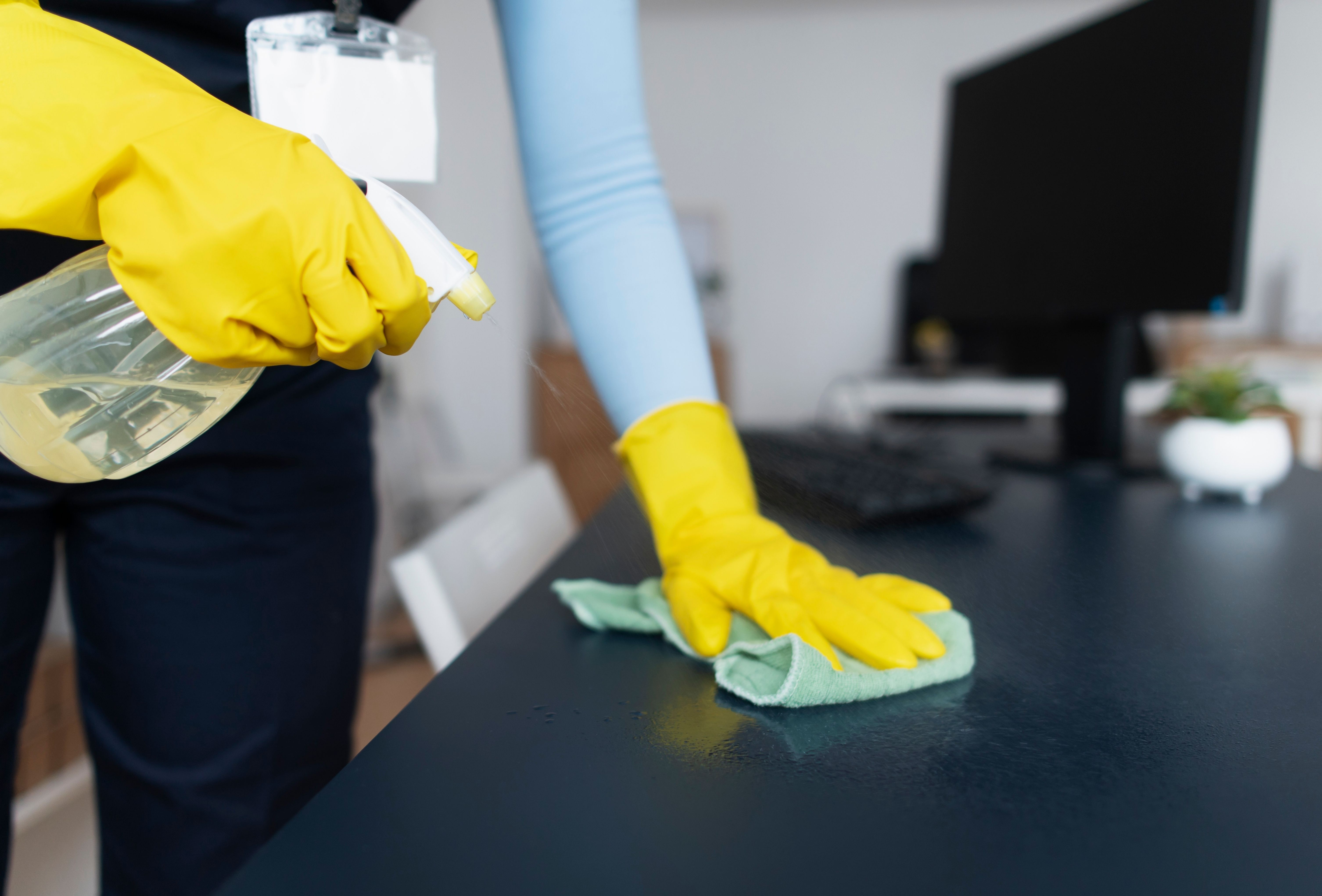 A worker from a cleaning service wiping down a household surface to reduce clutter. A worker from a cleaning service wiping down a household surface to reduce clutter.