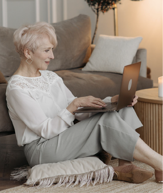 Older woman working on a laptop while seated at home.