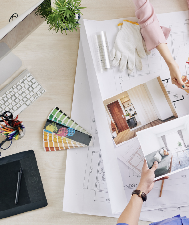 Designer reviewing business documents beside a desktop and palette.