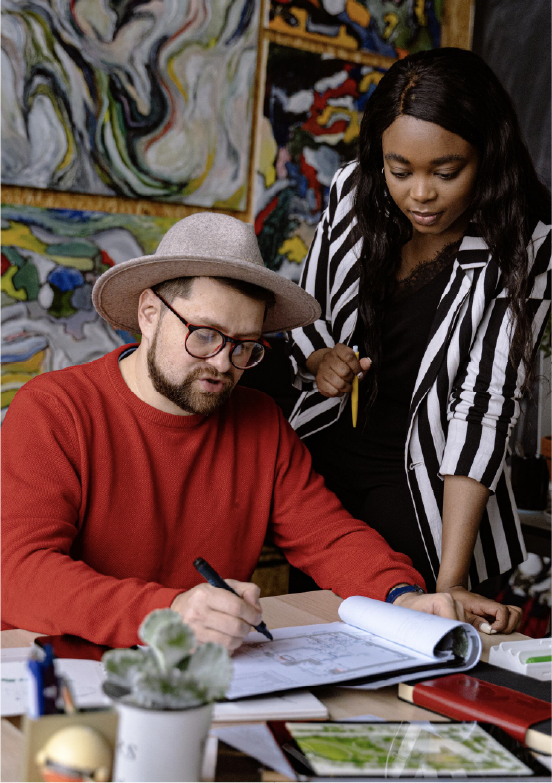 Creative team reviewing design plans together in a colorful studio.g late at a computer while drinking from a cup.