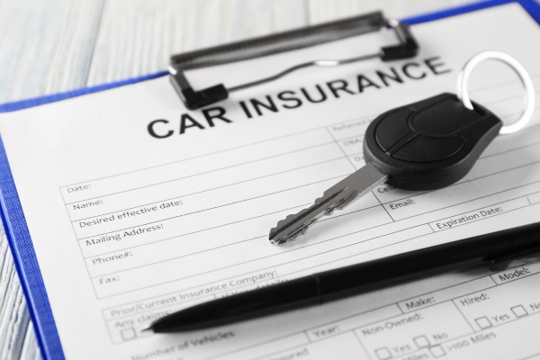 A close-up of someone reviewing insurance paperwork, with car keys nearby.