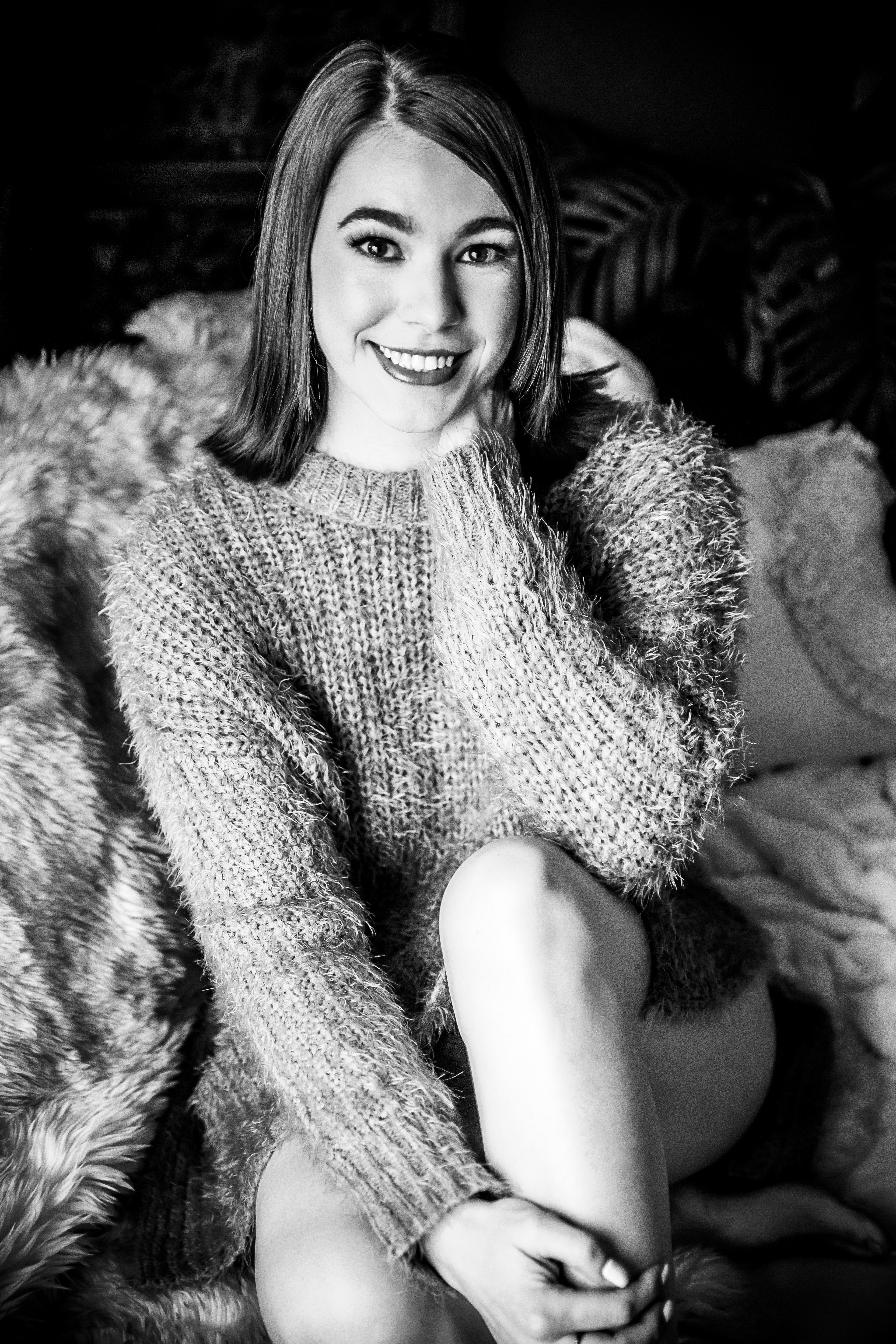 black and white photo of woman smiling while wearing sweater