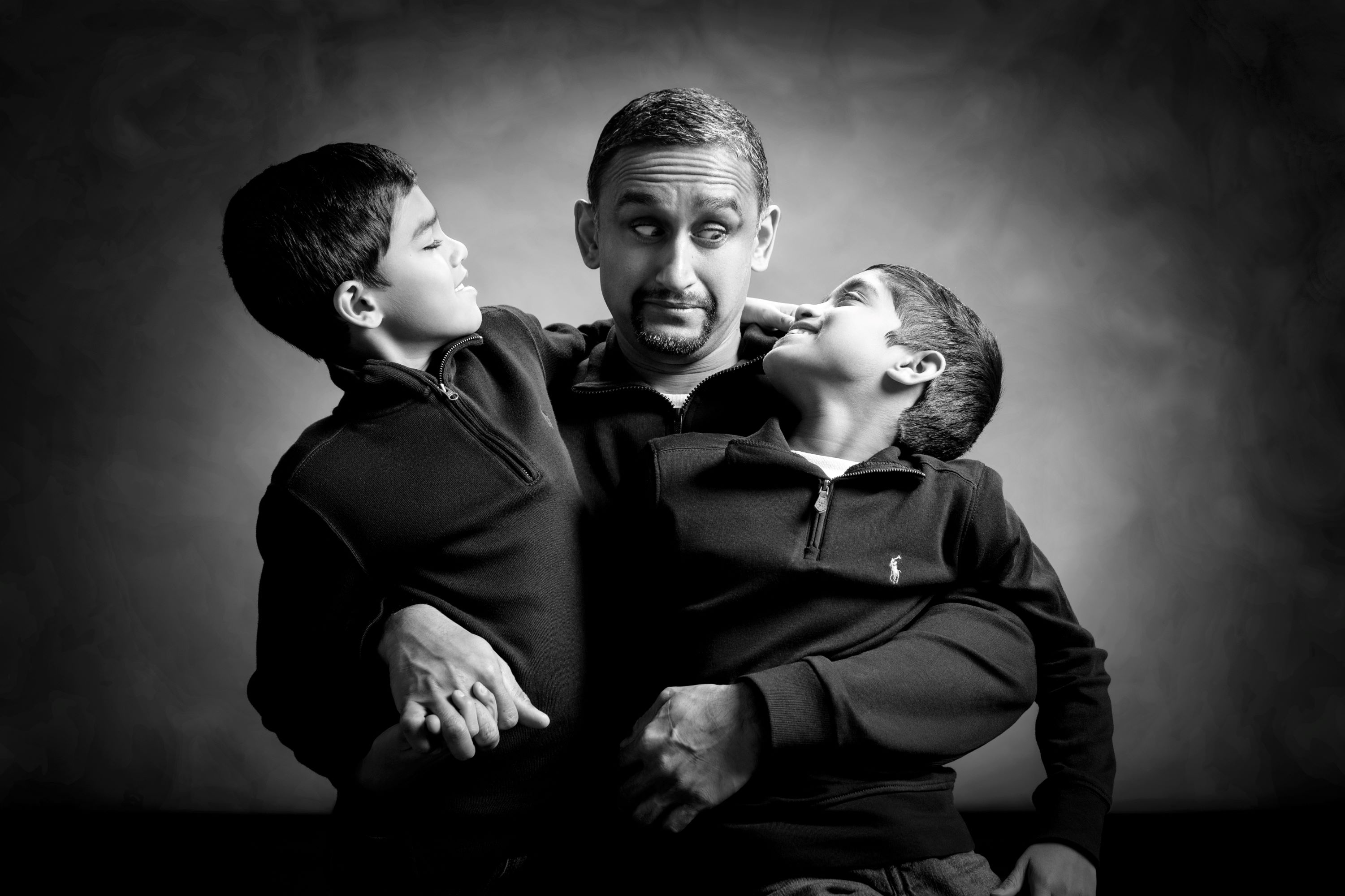 black and white studio portrait of father with two sons