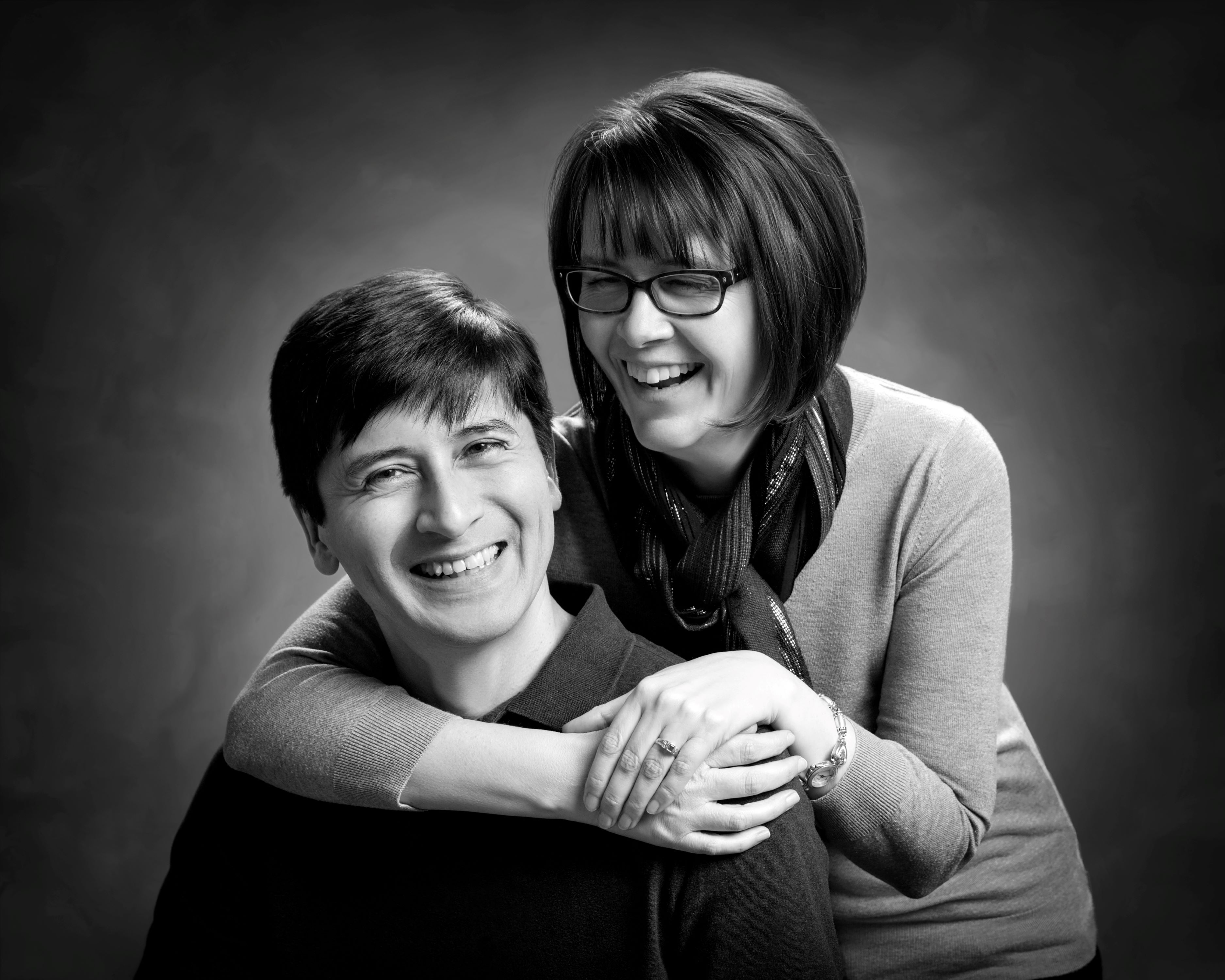 Black and white studio portrait of woman hugging a man