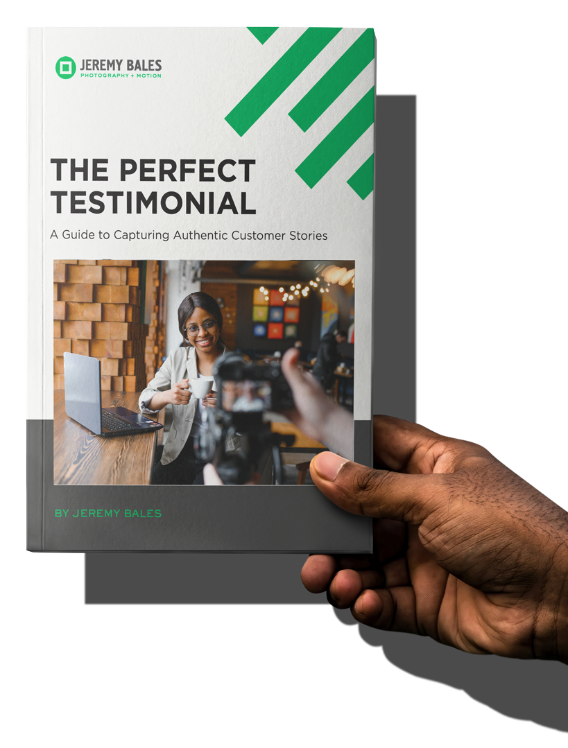 Printed copy of 'The Perfect Testimonial' held in hand, featuring cover design with woman holding tablet