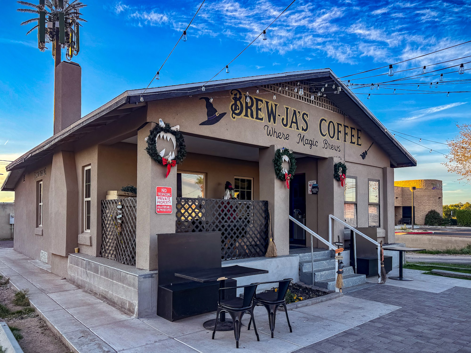 Brew-Ja's Coffee exterior during the day — full building, blue sky, string lights, patio chairs