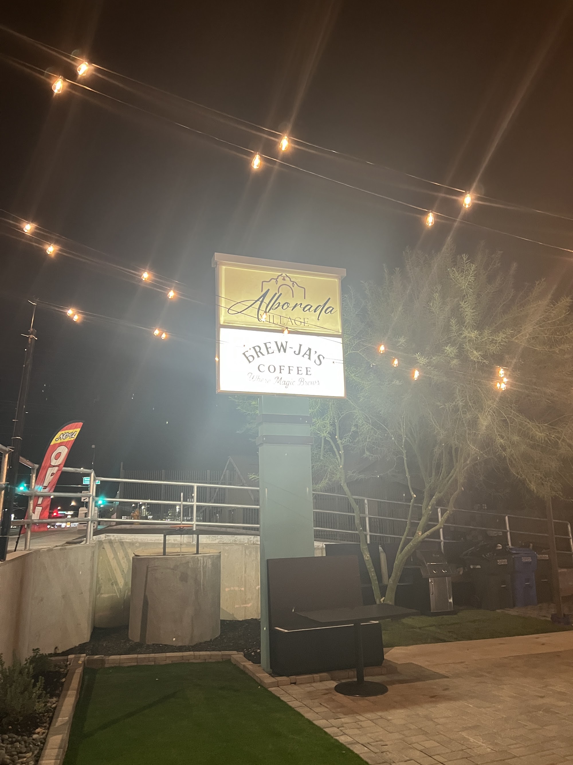 Alborada Village pylon sign with Brew-Ja's Coffee panel illuminated at night