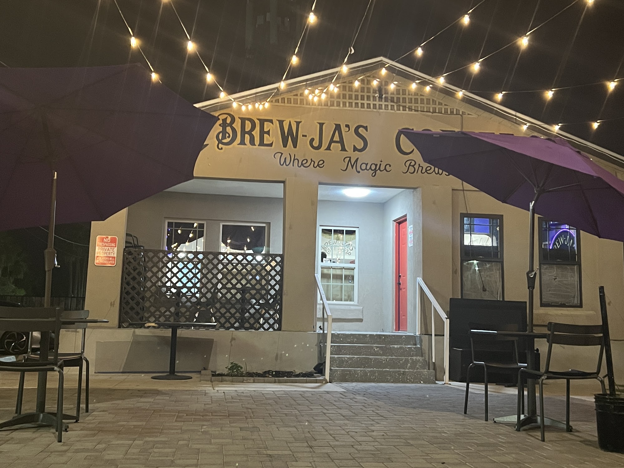 Brew-Ja's Coffee at night — red door entrance, string lights, purple patio umbrella