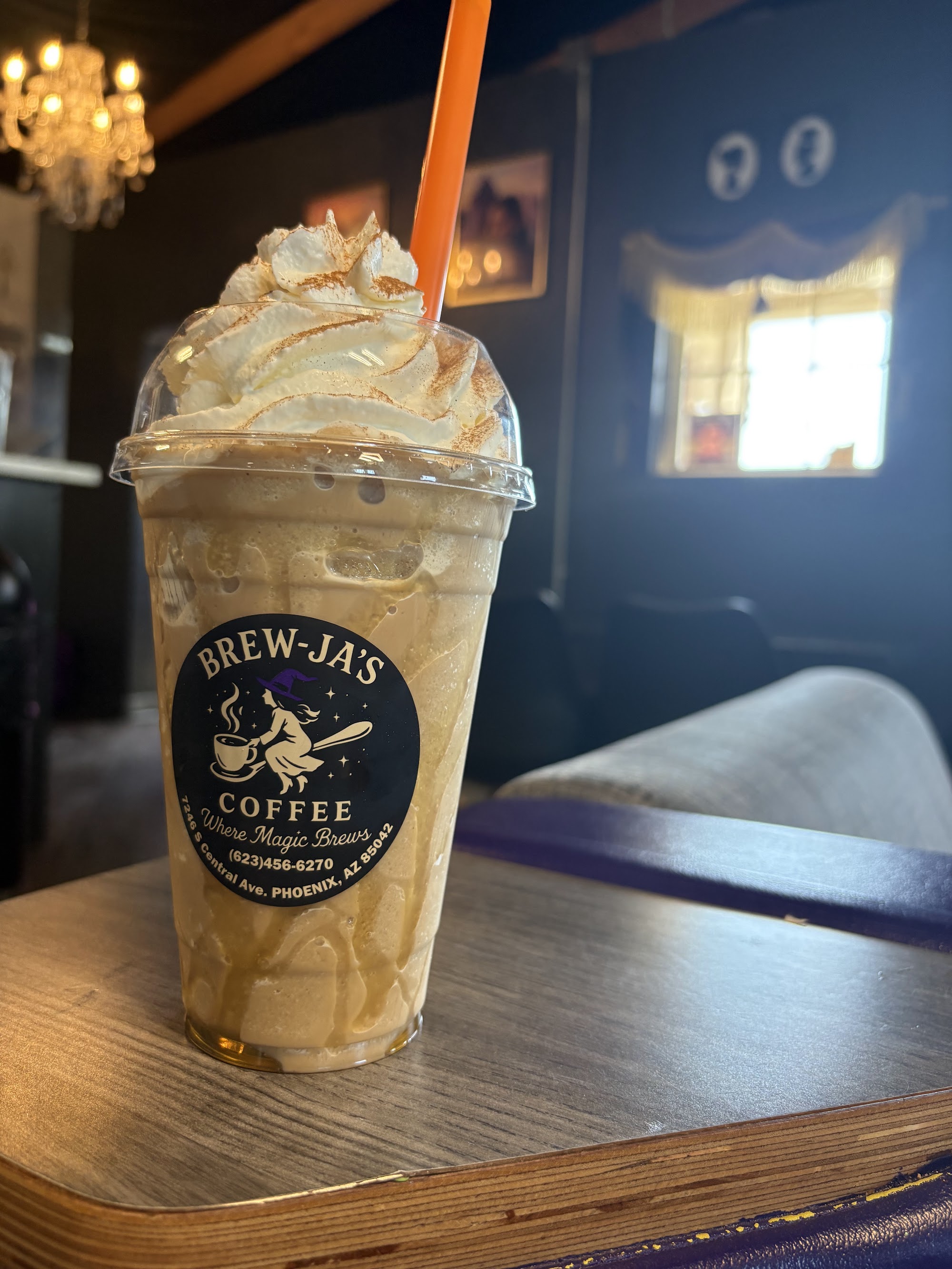 Caramel horchata frappe on wooden table with chandelier and decor in background