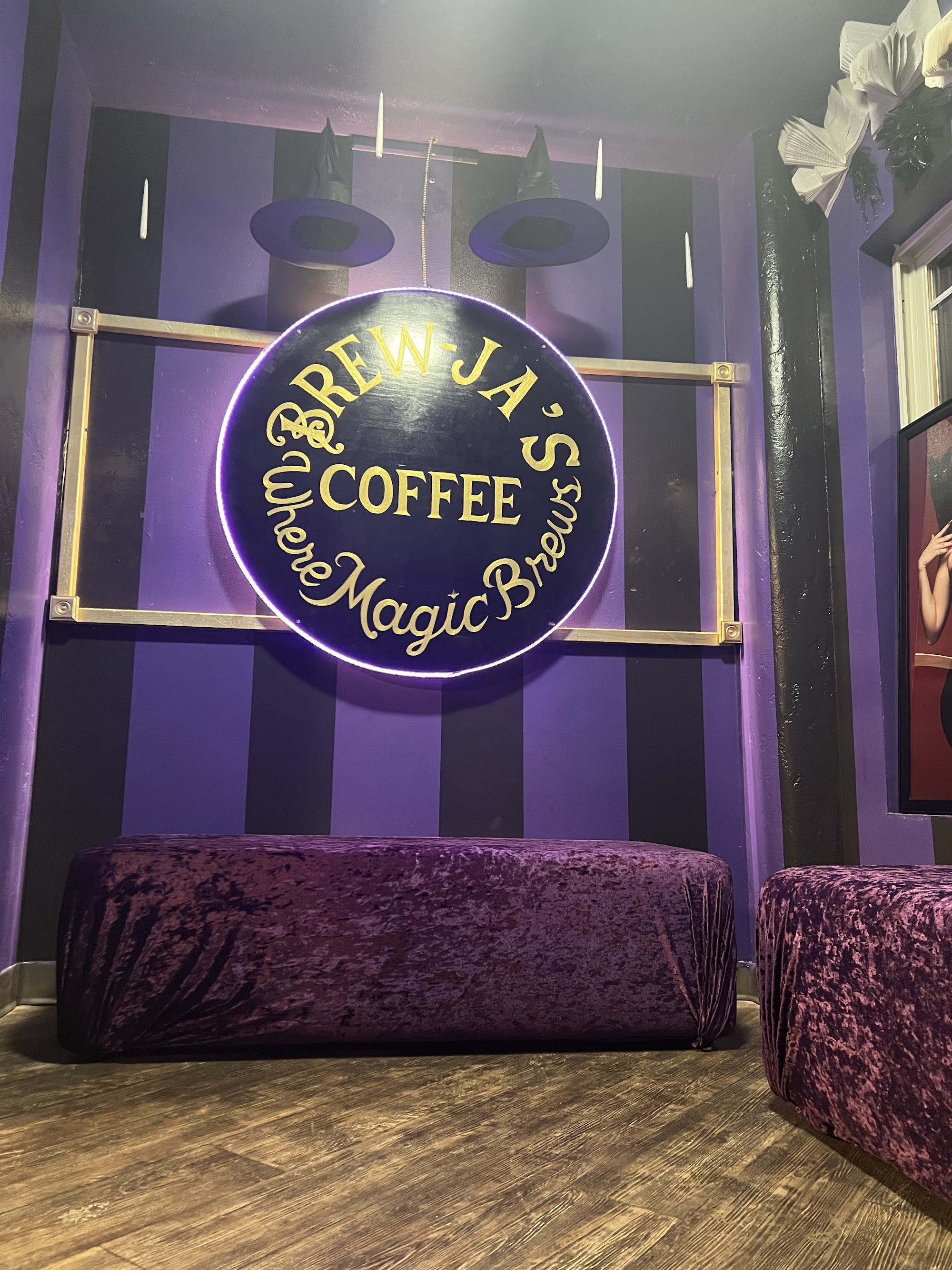 Purple lounge at Brew-Ja's Coffee — illuminated neon circle sign, velvet benches, witchy atmosphere