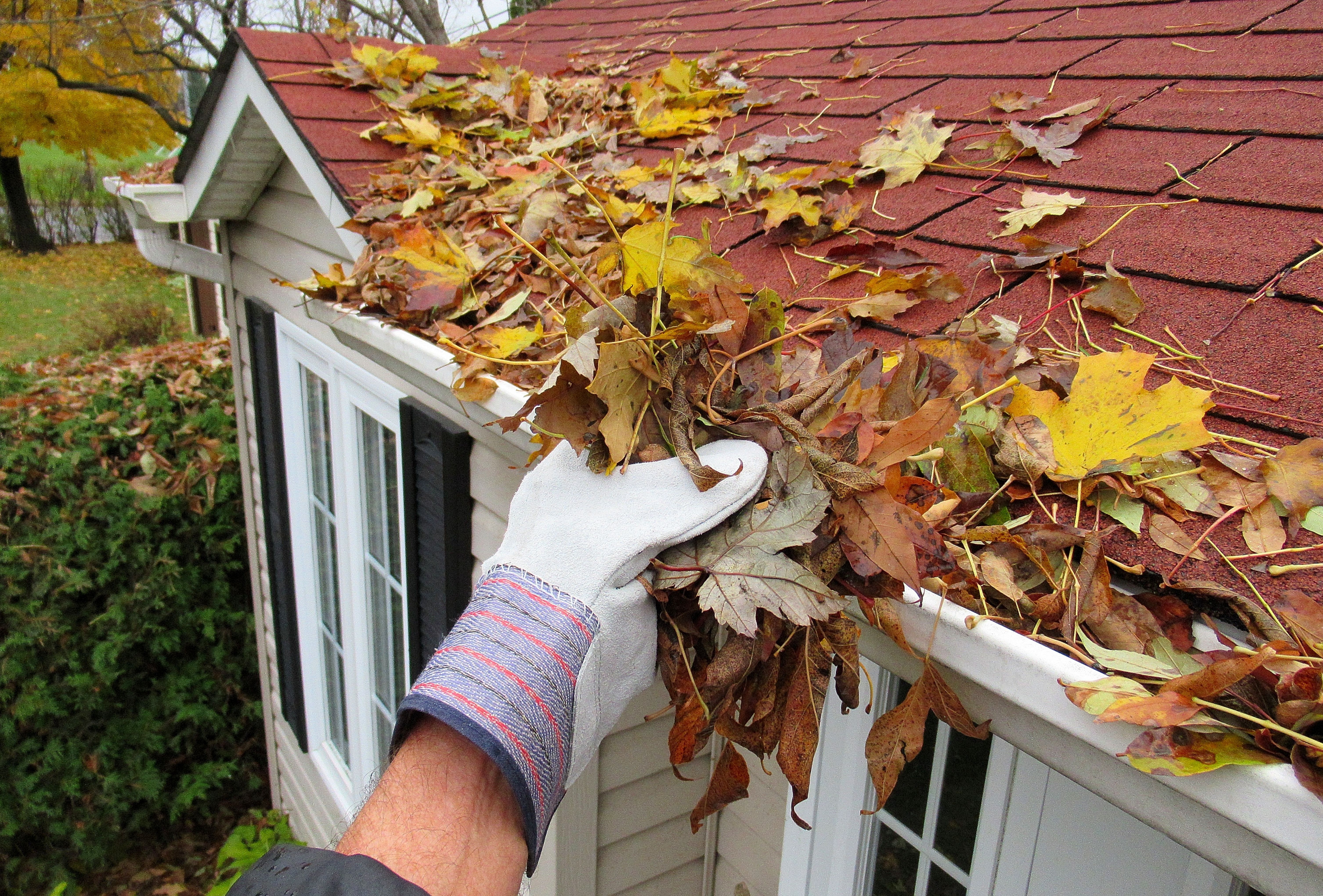 A roofer wearing safety gear while performing gutter cleaning Wisconsin. A roofer wearing safety gear while performing gutter cleaning Wisconsin.