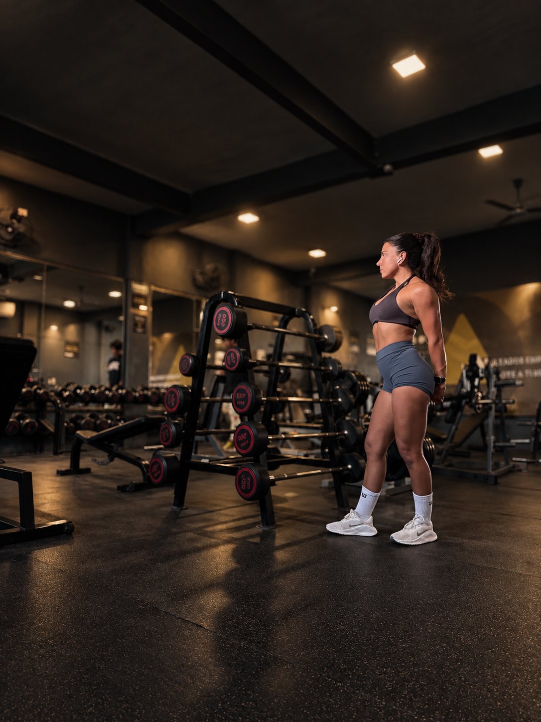 Ignacia de pie de perfil en el gimnasio, junto a un rack de barras