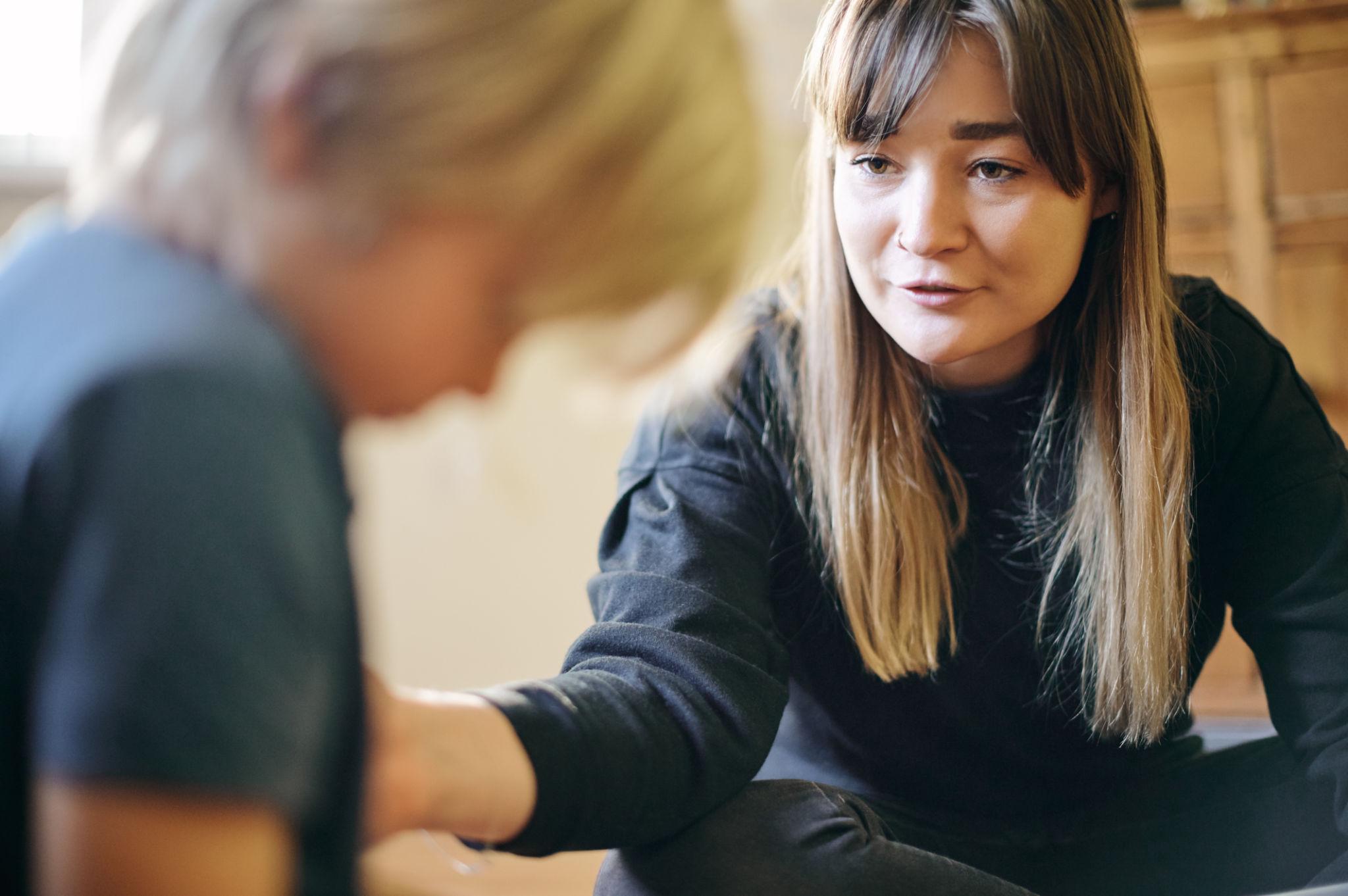 Therapist working closely with child during autism spectrum disorder therapy session, providing guidance and support