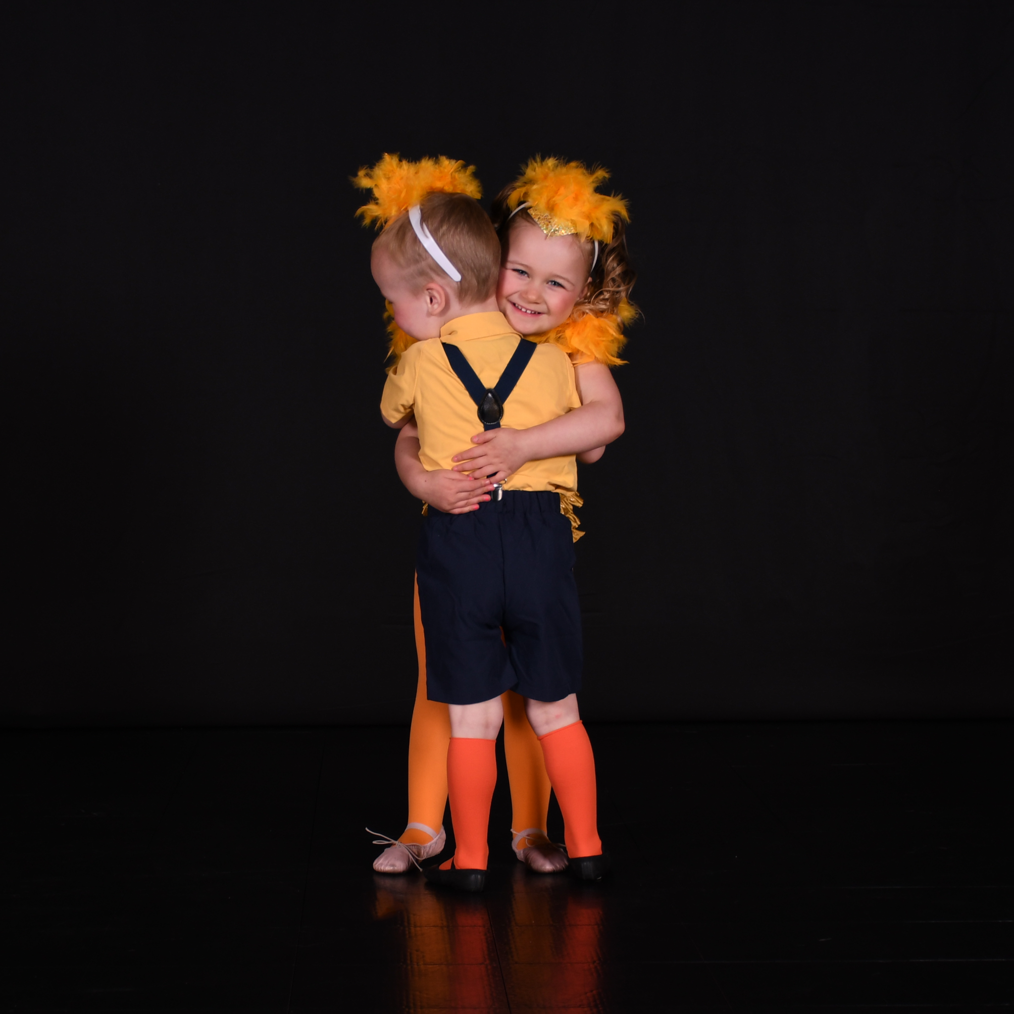 Two young Kore dancers hugging in yellow Disco Ducks costumes