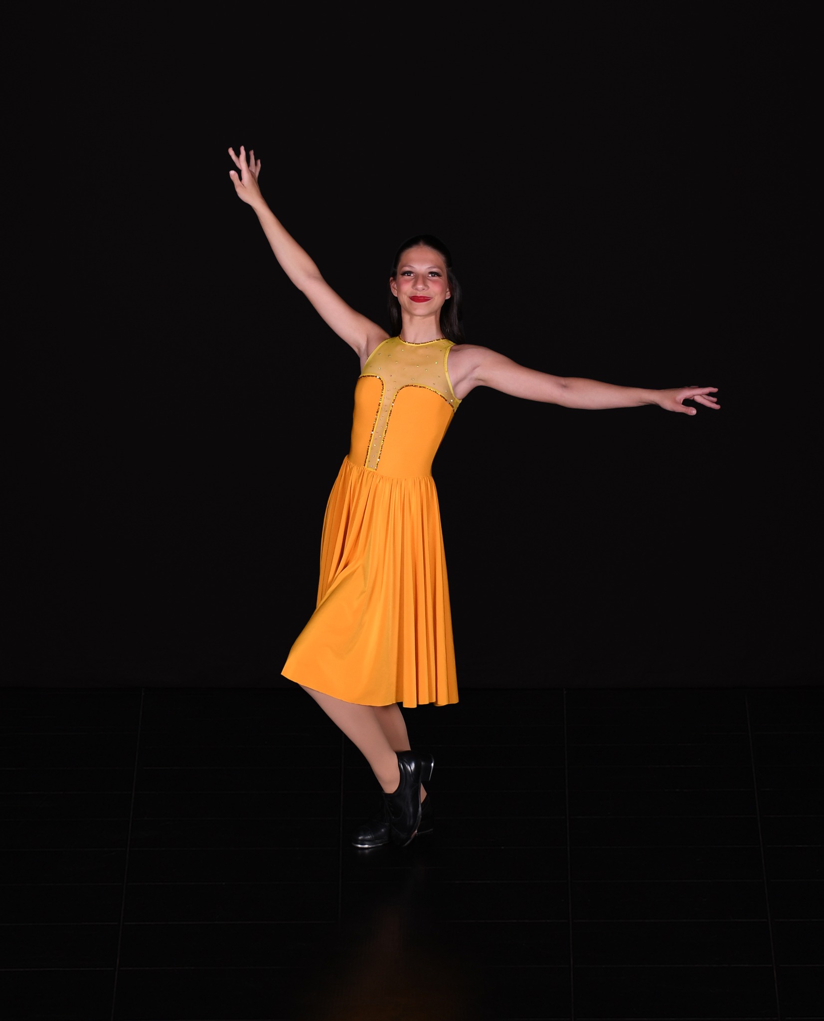Kore dancer smiling in a yellow dress with arms extended