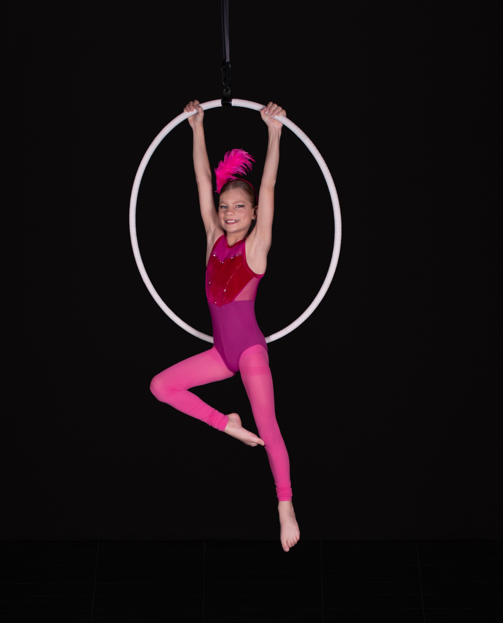 Kore aerial dancer posing on a hoop in a pink costume