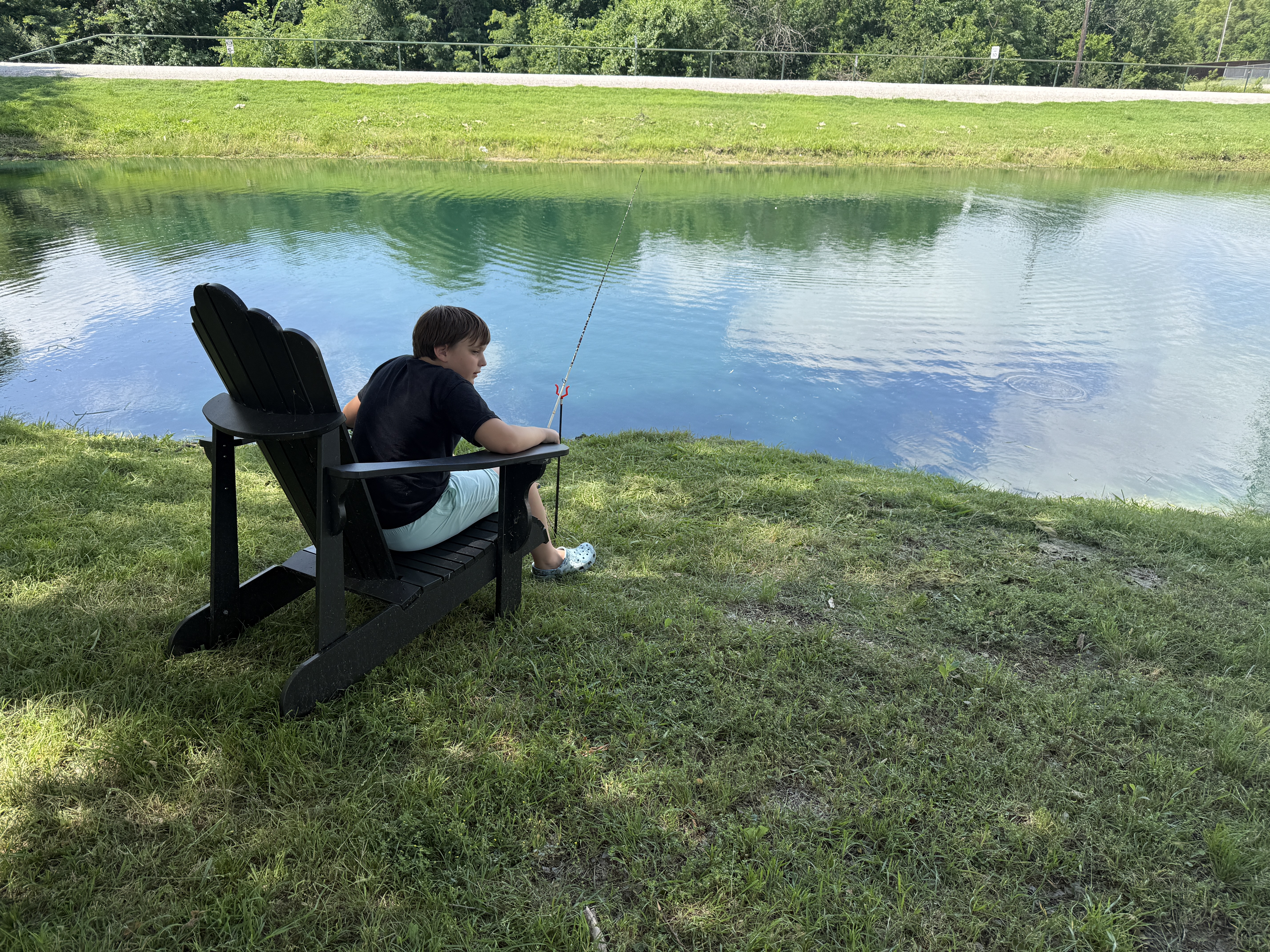 Kid fishing from an Adirondack chair at the Countryview private pond