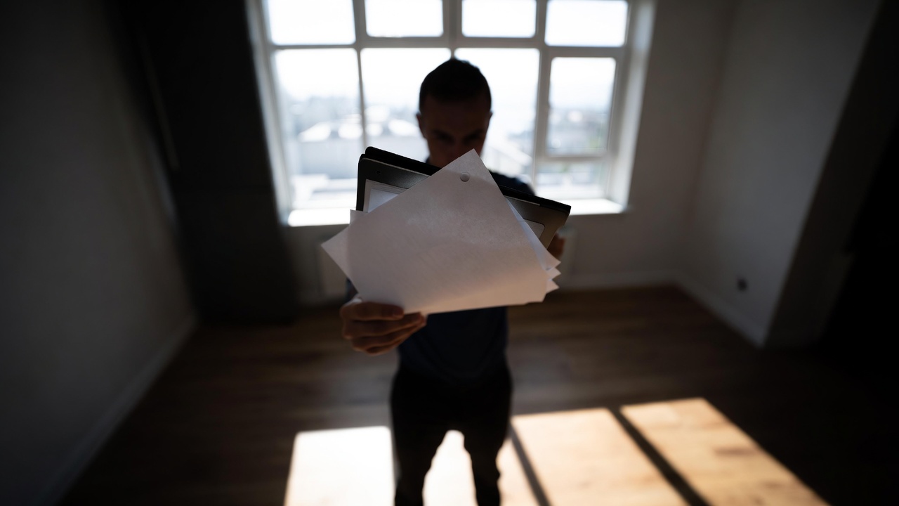 Person holding real estate paperwork and documents in an empty home, representing contract review and closing preparation