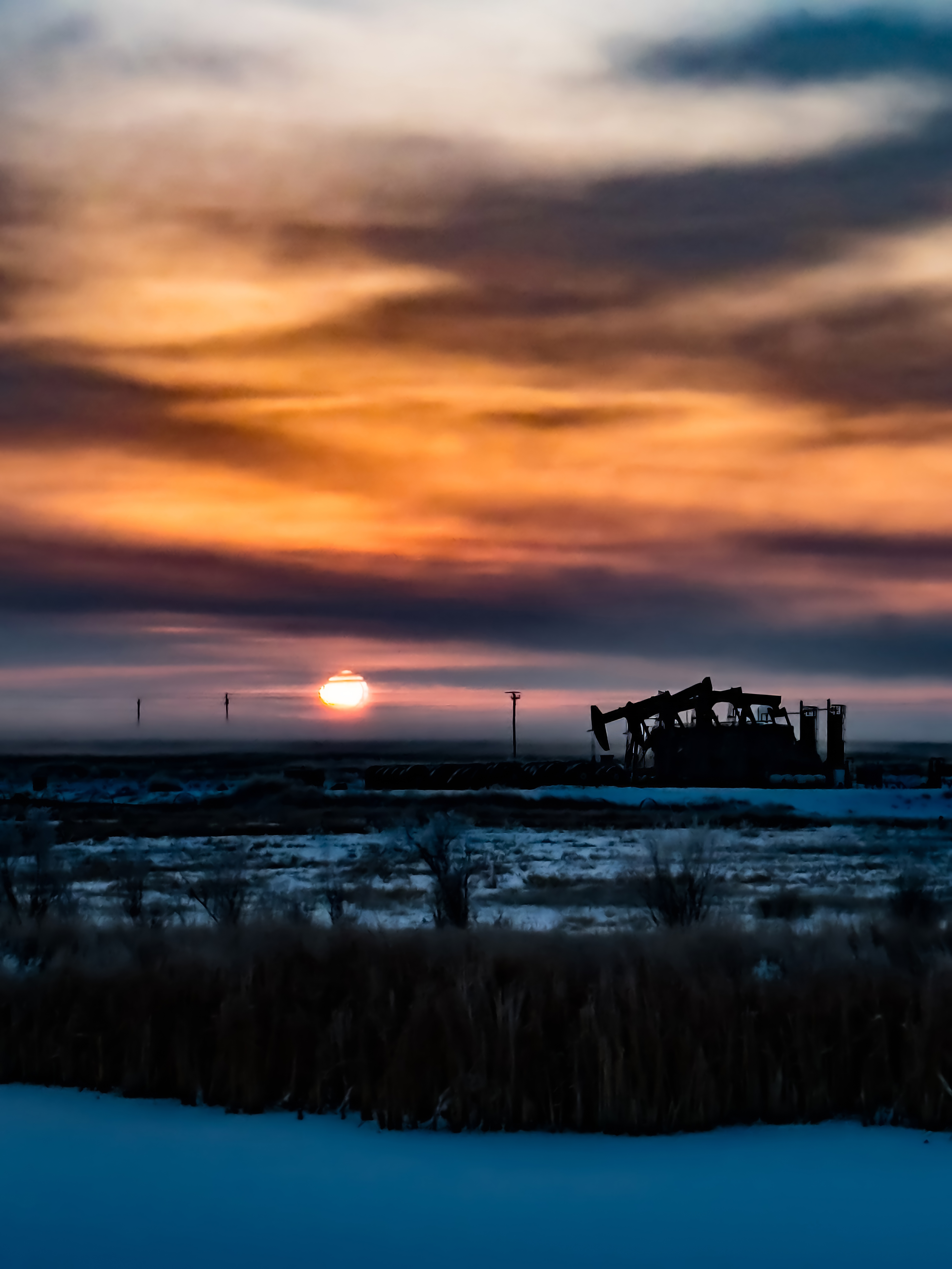 Oil field pump jack at sunset in the Uintah Basin