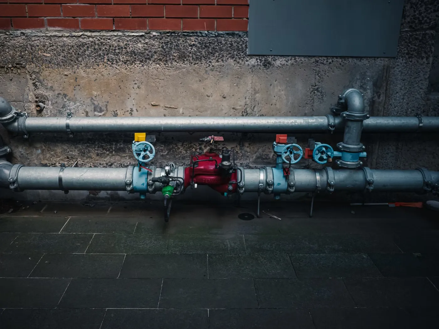 Industrial pipes with coloured valves against a wall