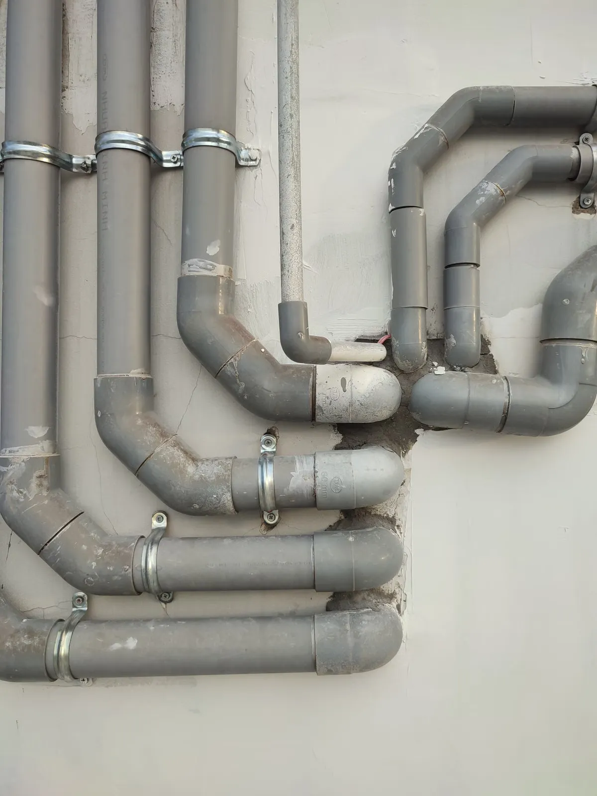 Interconnected grey metal pipes on an exterior wall