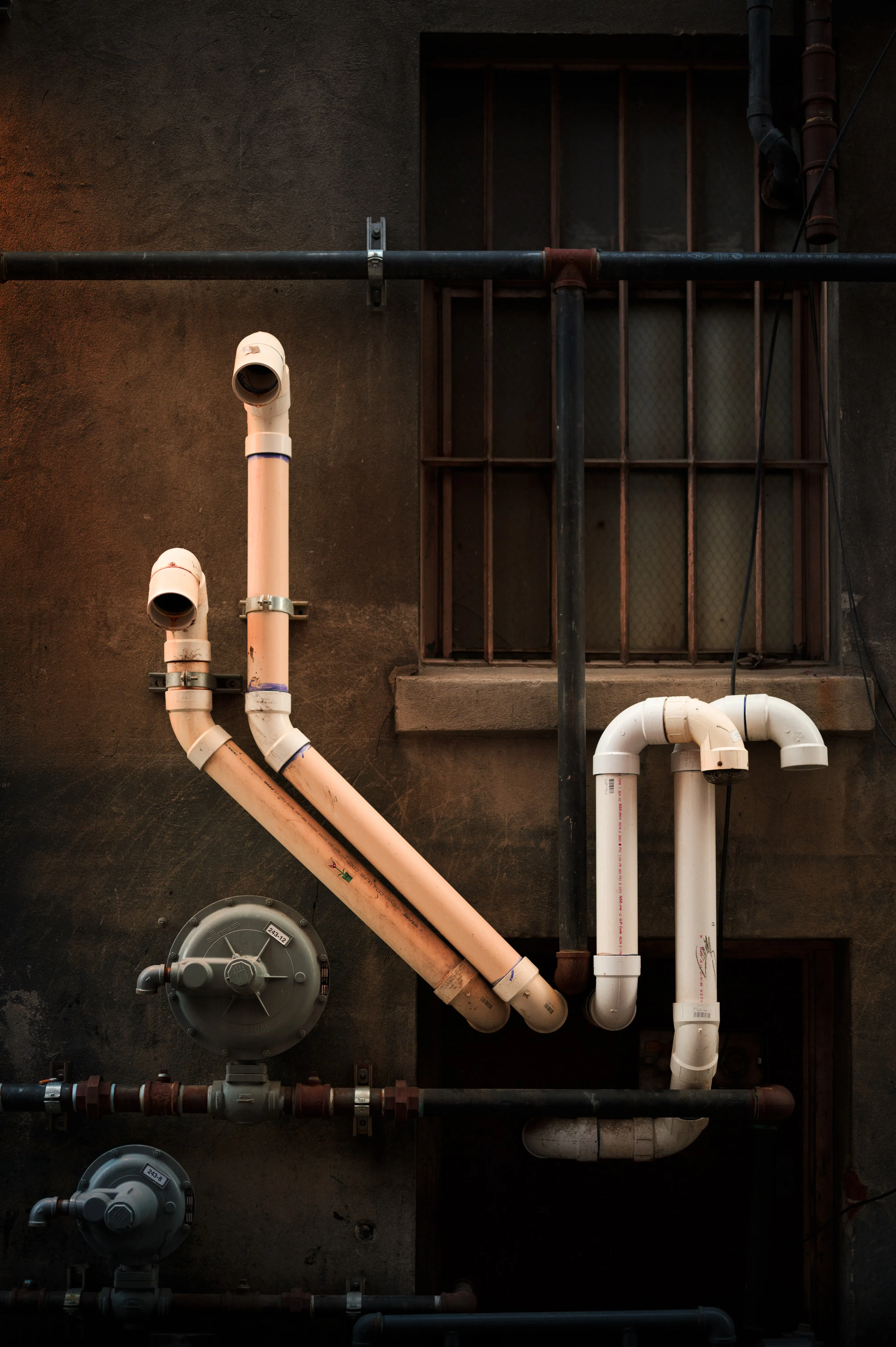 Vertical run of industrial pipework on a building wall